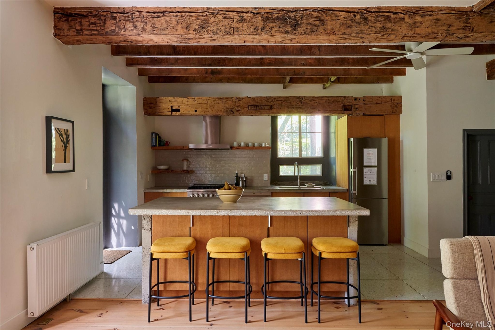 Kitchen with radiator heating unit, a kitchen breakfast bar, light countertops, stainless steel appliances, and beamed ceiling