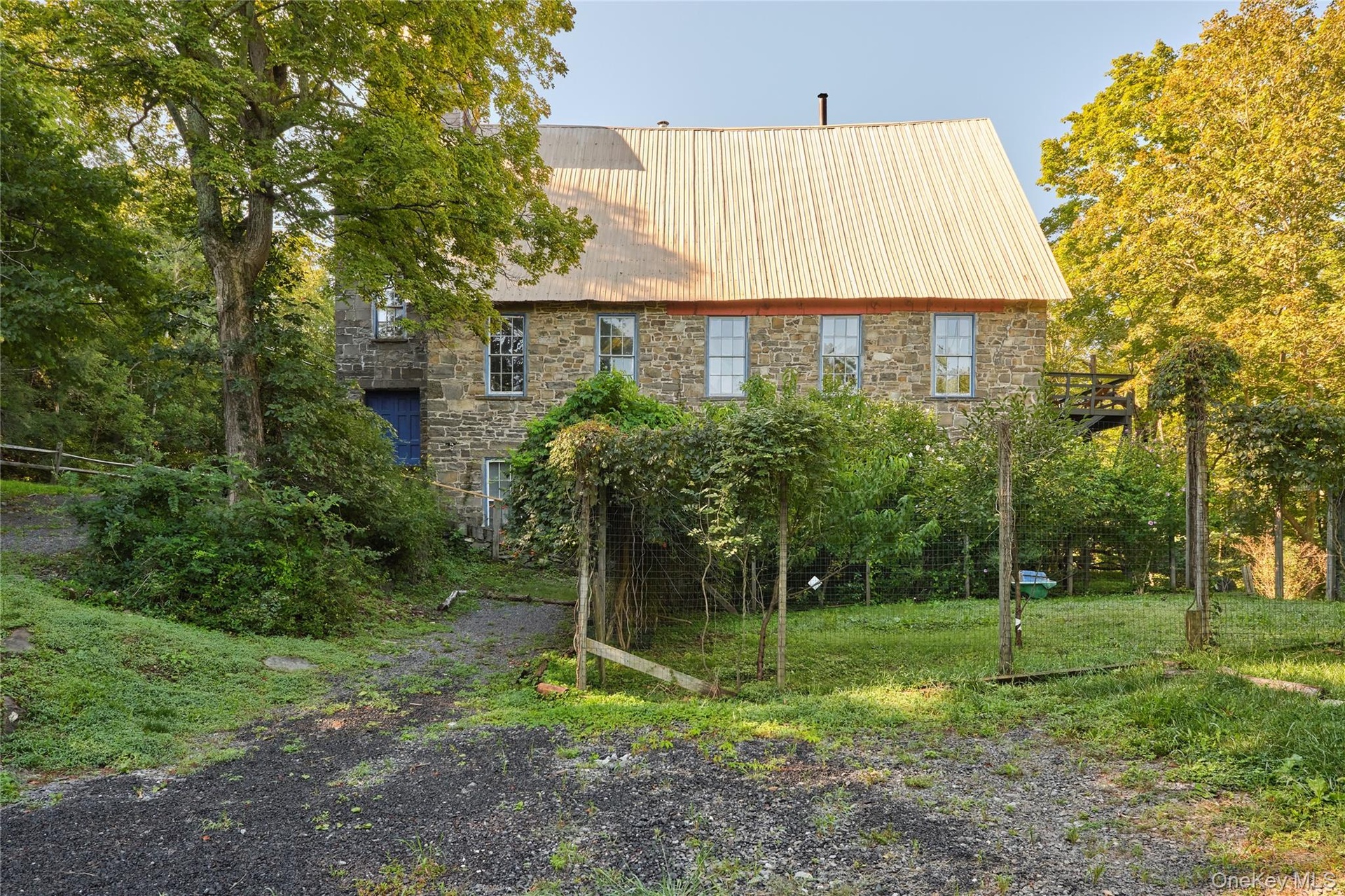 Back of house featuring stone siding and a metal roof