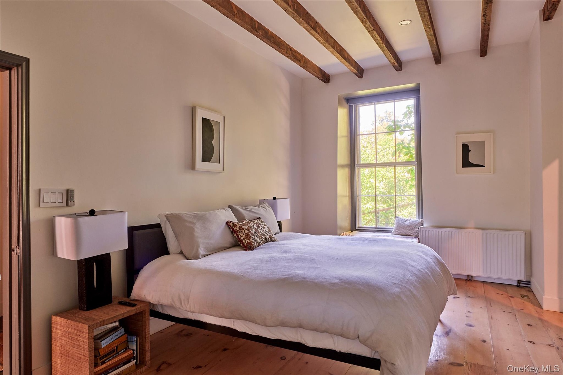 Bedroom featuring radiator, beam ceiling, and hardwood / wood-style flooring