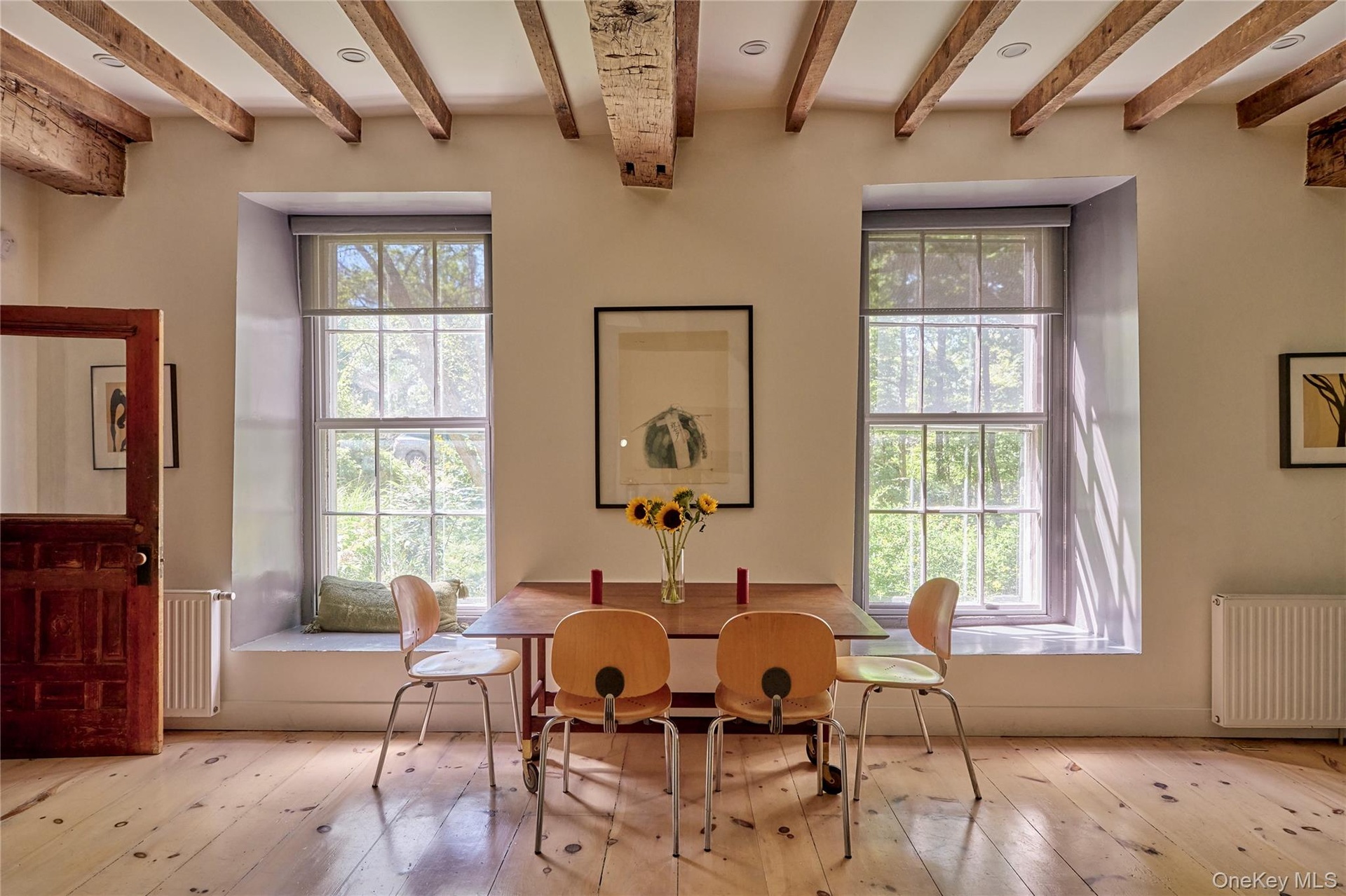 Dining area featuring radiator heating unit, beam ceiling, and hardwood / wood-style flooring