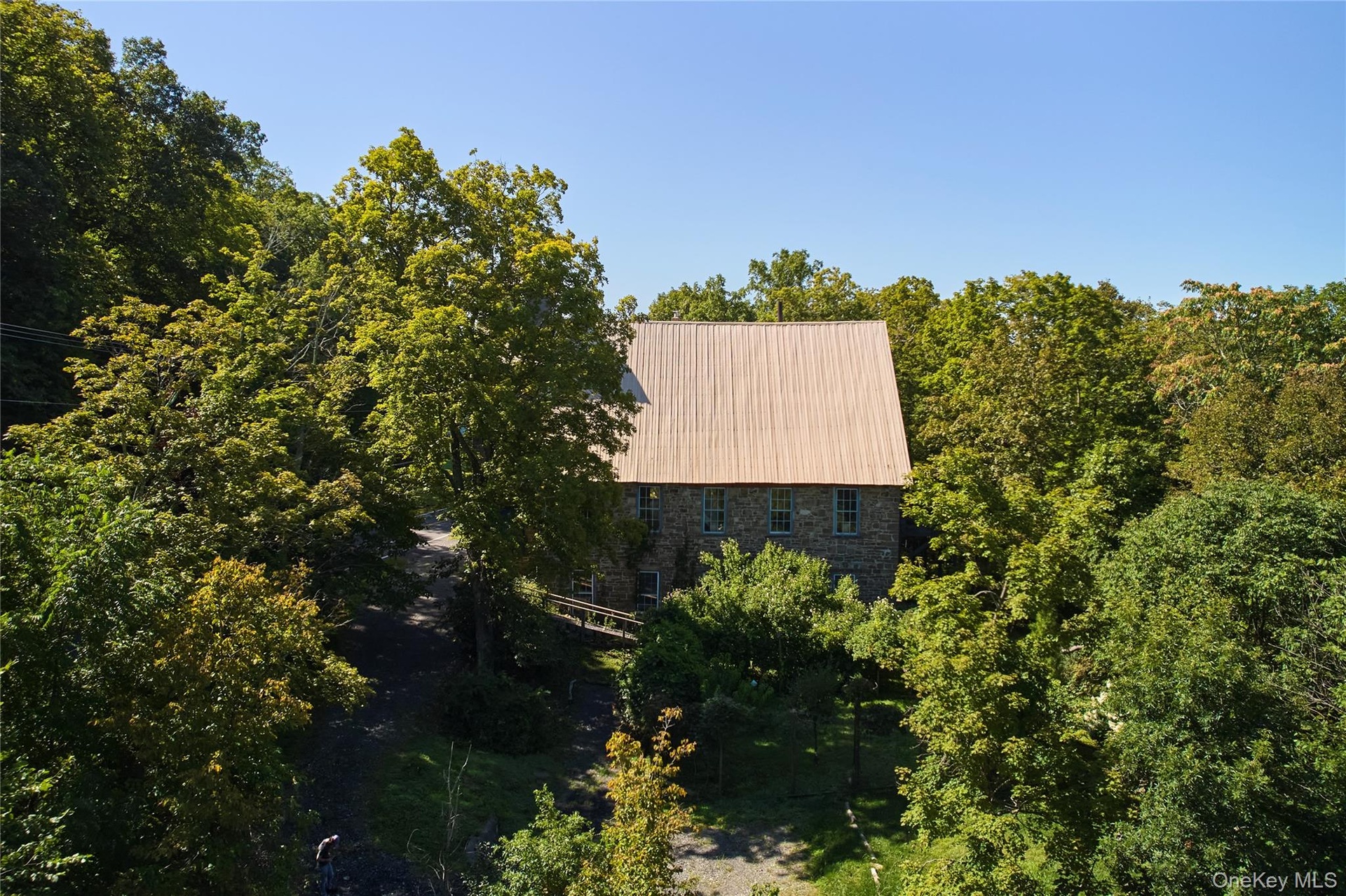 Aerial view of property and surrounding area with a forest