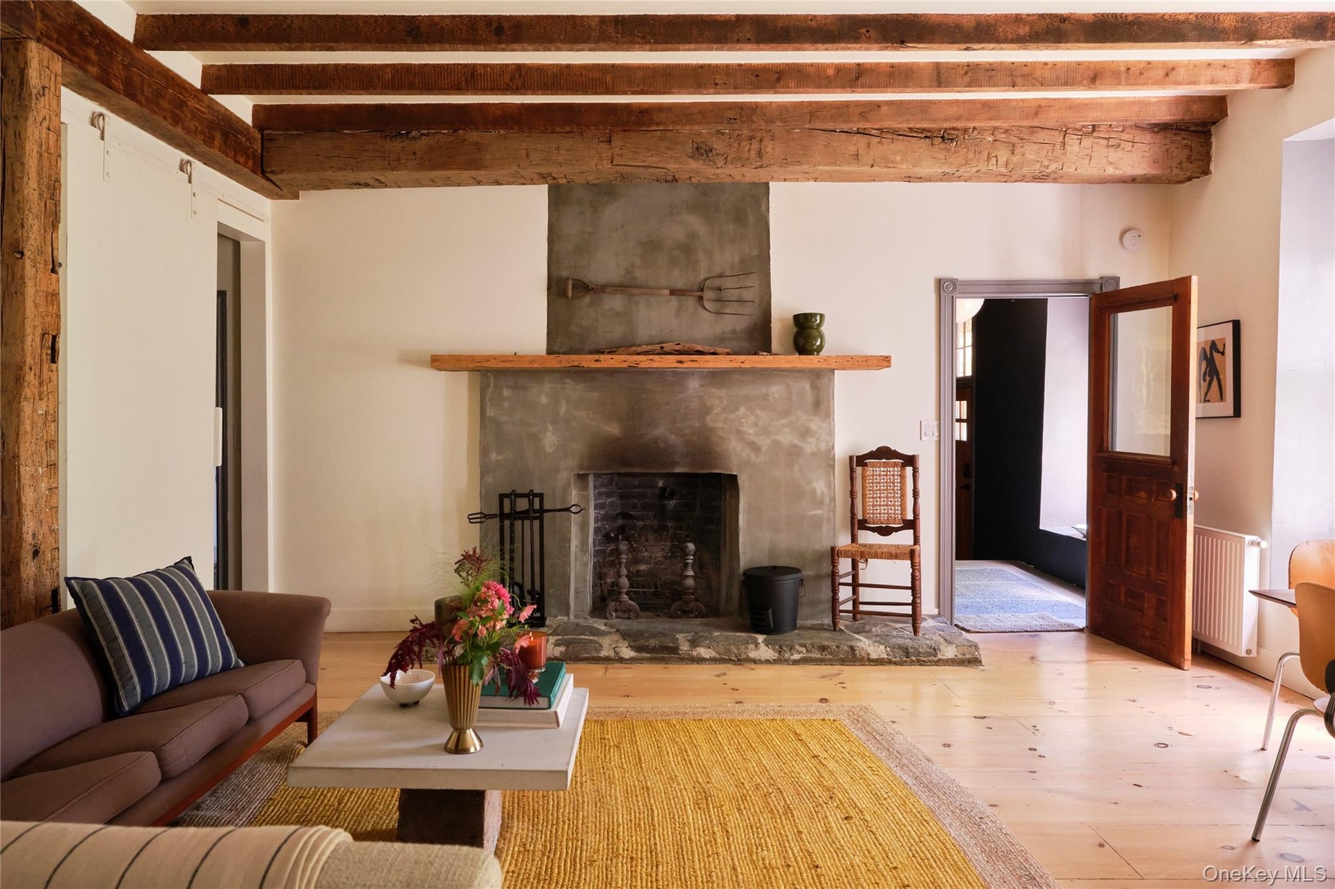 Living area with a premium fireplace, beamed ceiling, radiator, and hardwood / wood-style flooring