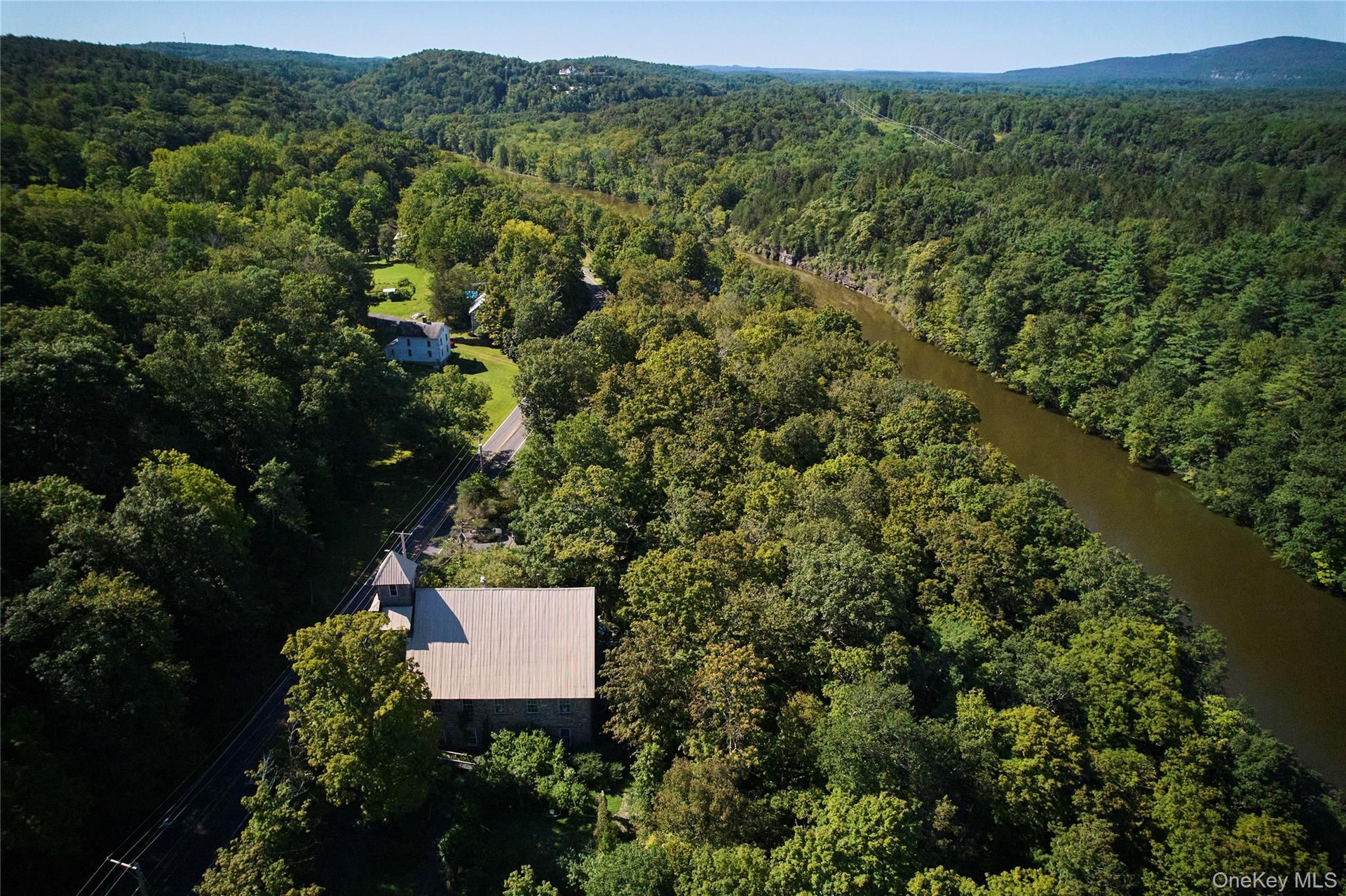 Aerial view of property and surrounding area featuring a forest and a large body of water