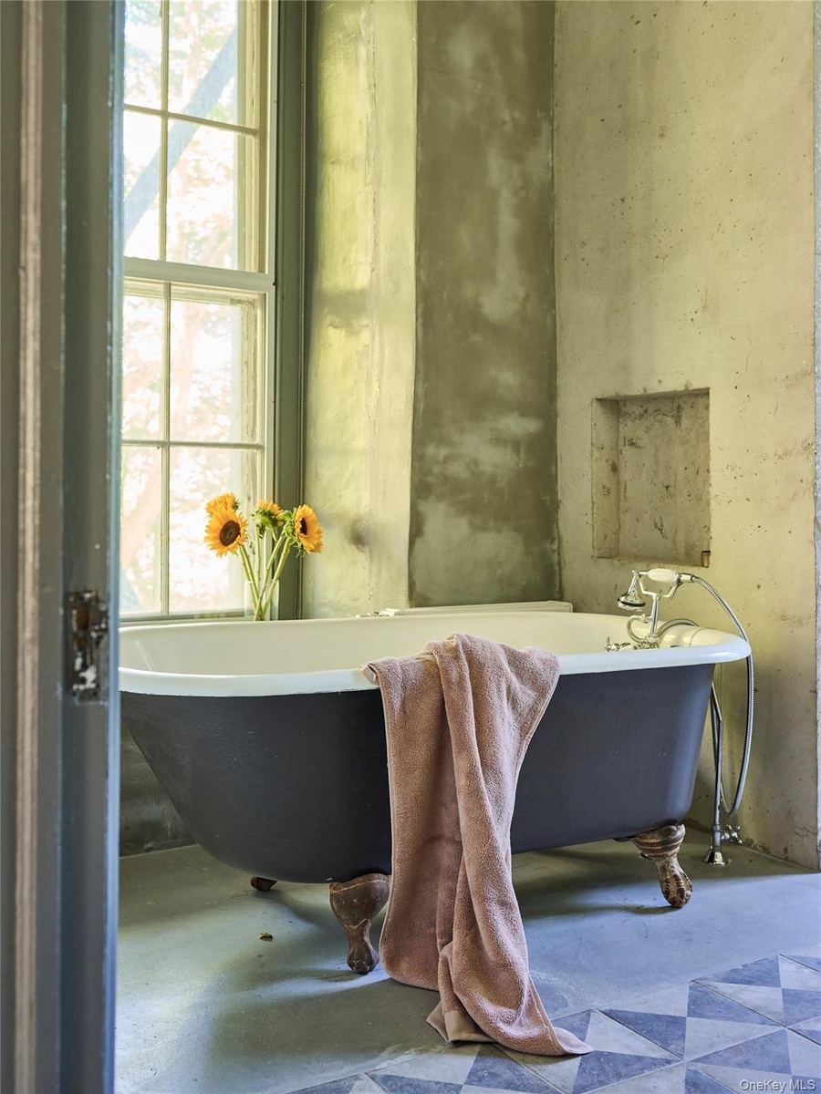 Bathroom featuring a freestanding tub and concrete floors