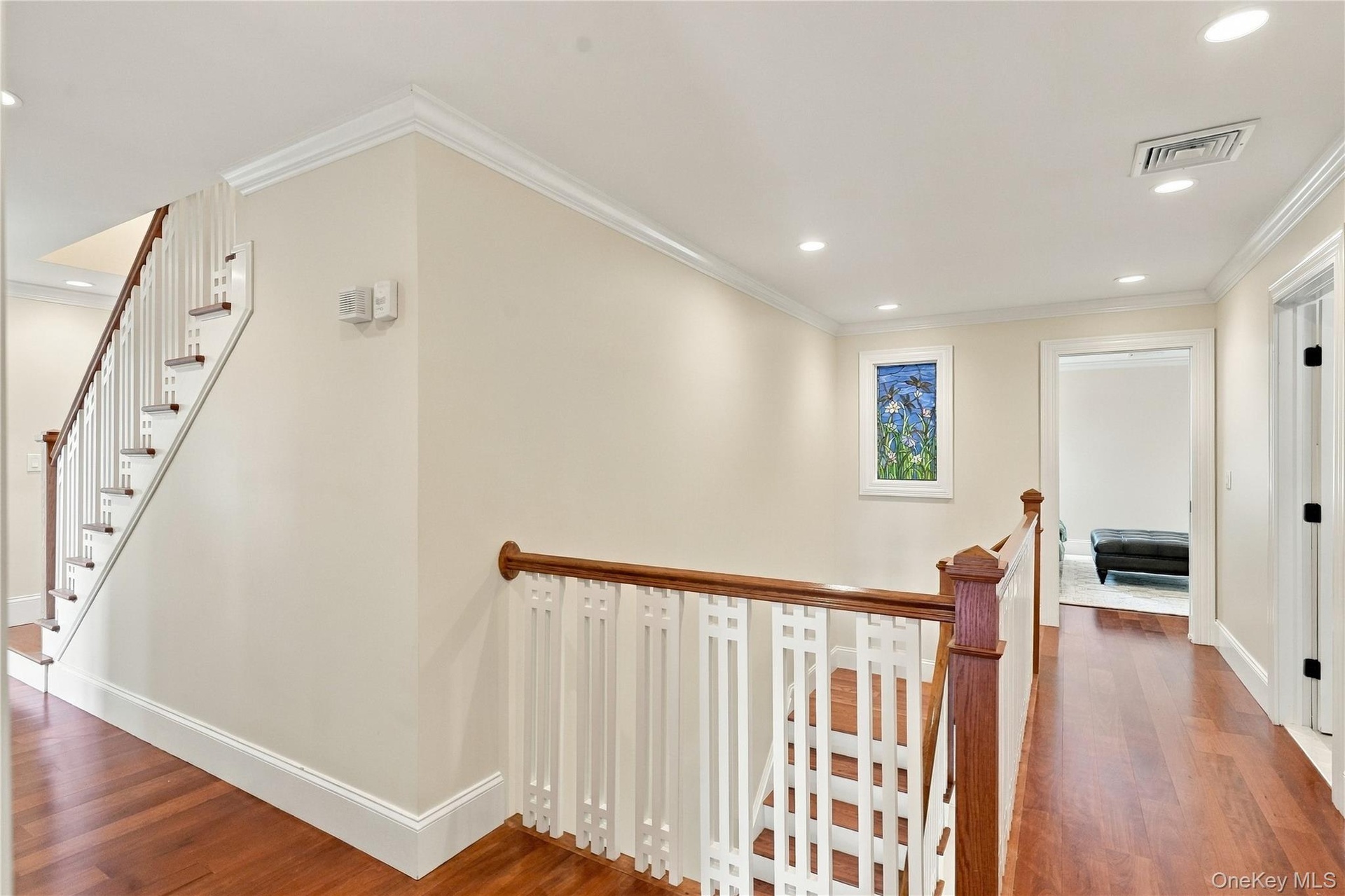 A beautifully crafted staircase featuring hand-drawn detailing, decorative white balusters, and a stunning stained-glass window, showcasing the home's