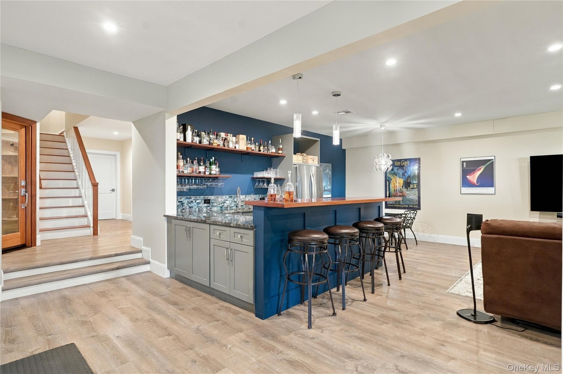 A beautifully designed lower-level entertainment lounge featuring a custom bar with a rich mahogany countertop, built-in refrigeration, a third Bosch 