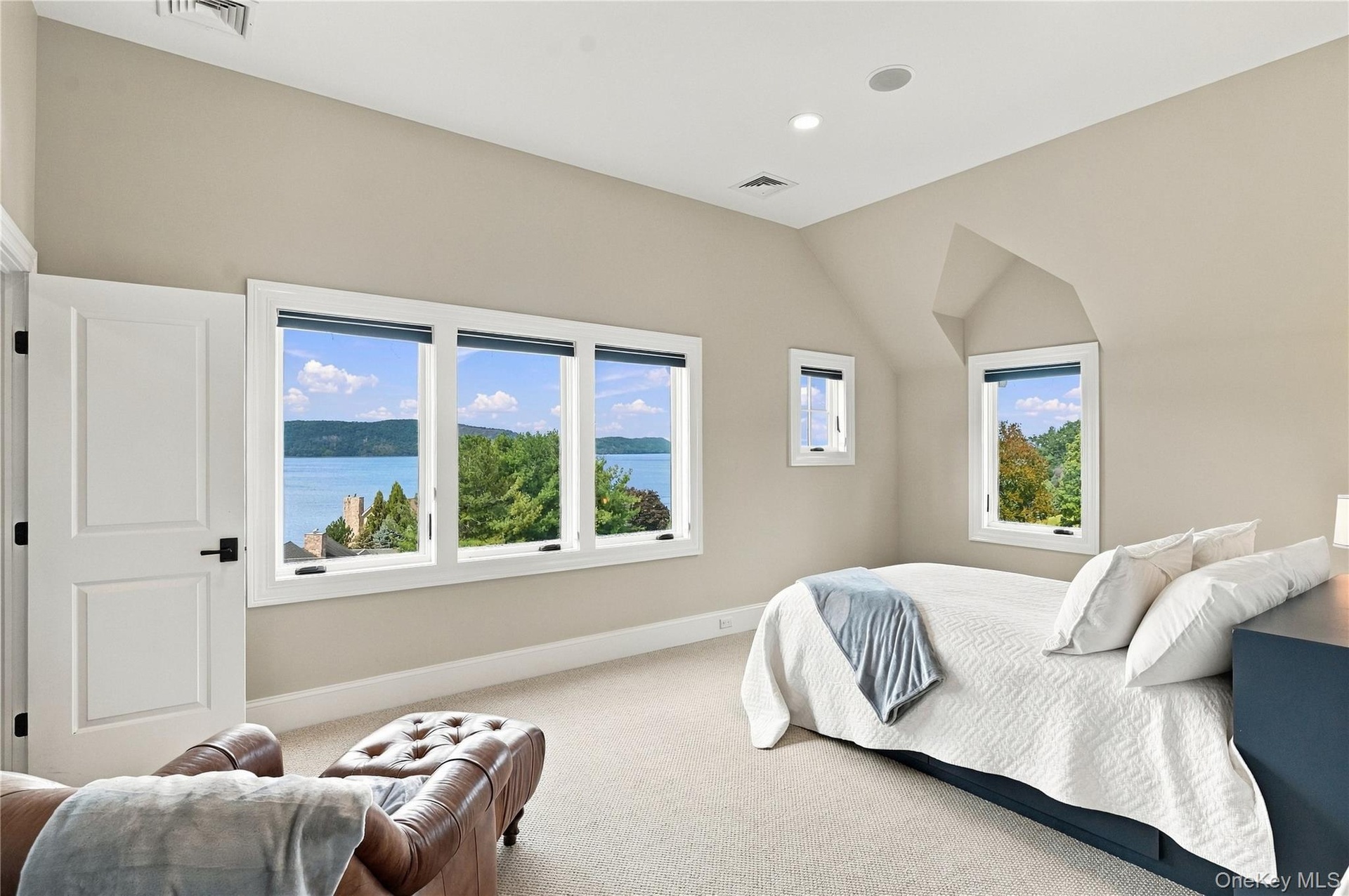 A oversized, light-filled bedroom featuring beautiful architectural details and expansive windows showcasing breathtaking Hudson River views with en s