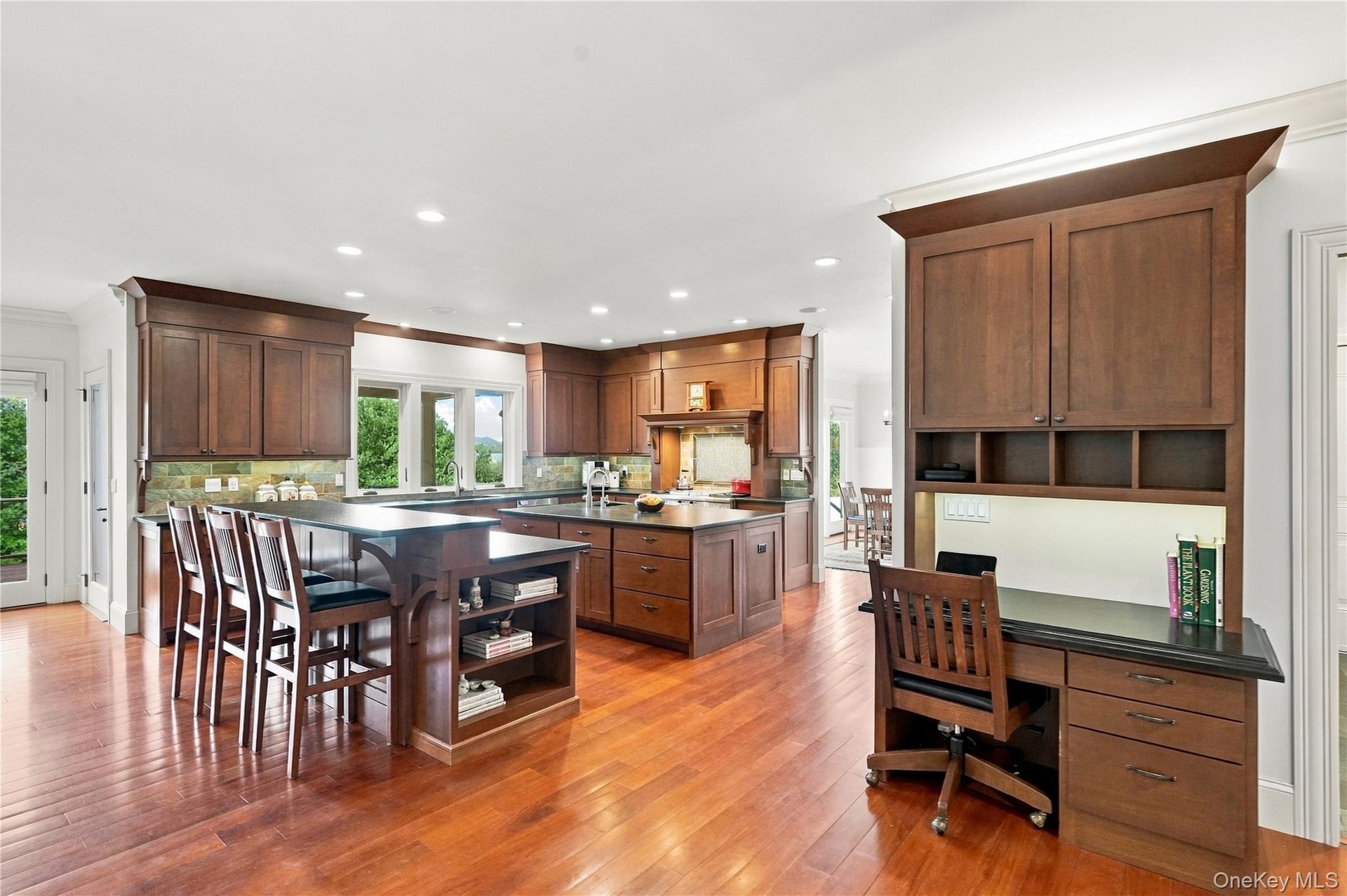 A beautifully designed gourmet kitchen featuring custom cherry cabinetry, dual islands with breakfast bar seating, rich hardwood floors, and a built-i