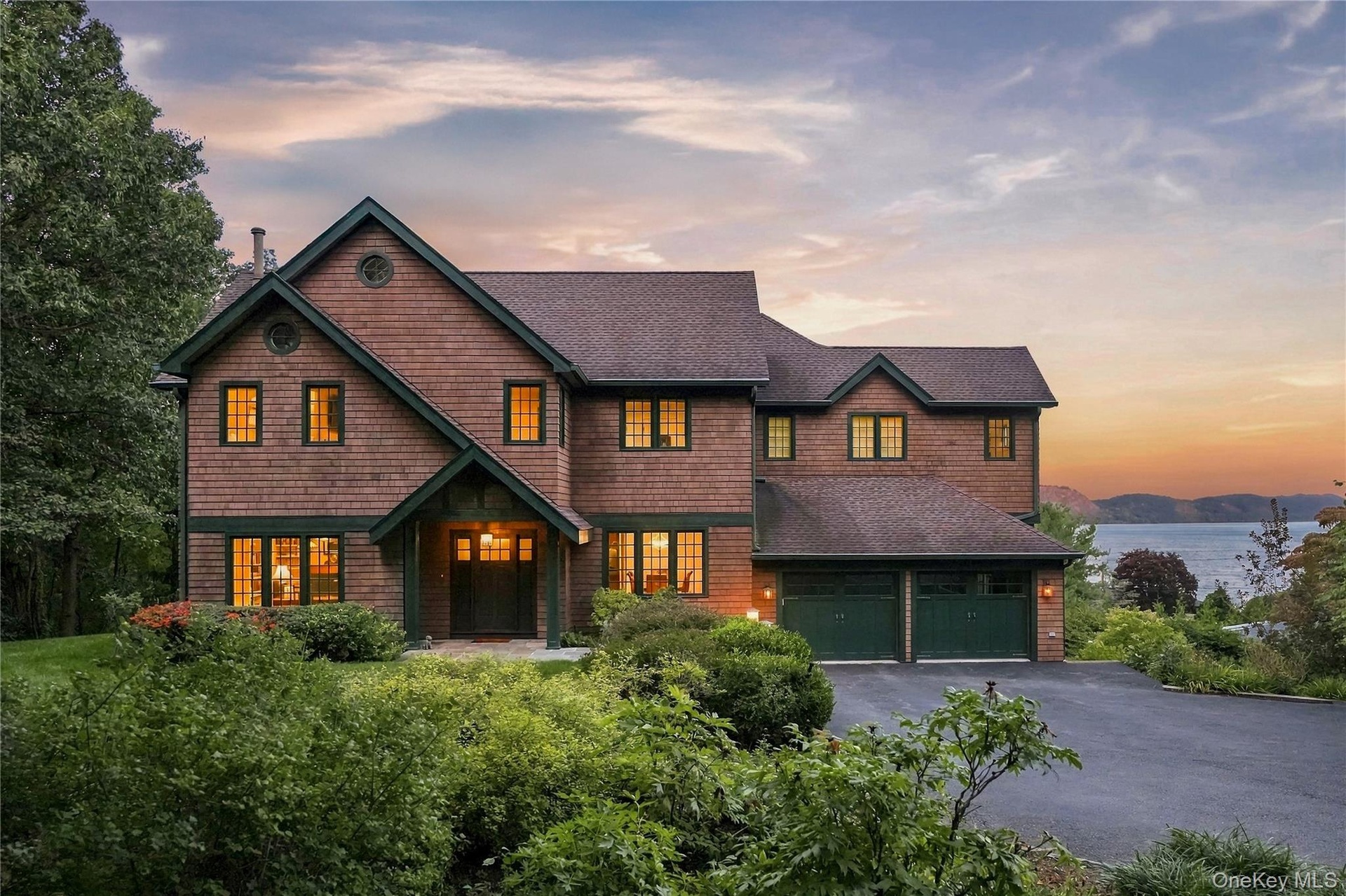 A striking Colonial residence framed by lush landscaping, with warm architectural lighting and breathtaking Hudson River views creating an unforgettab