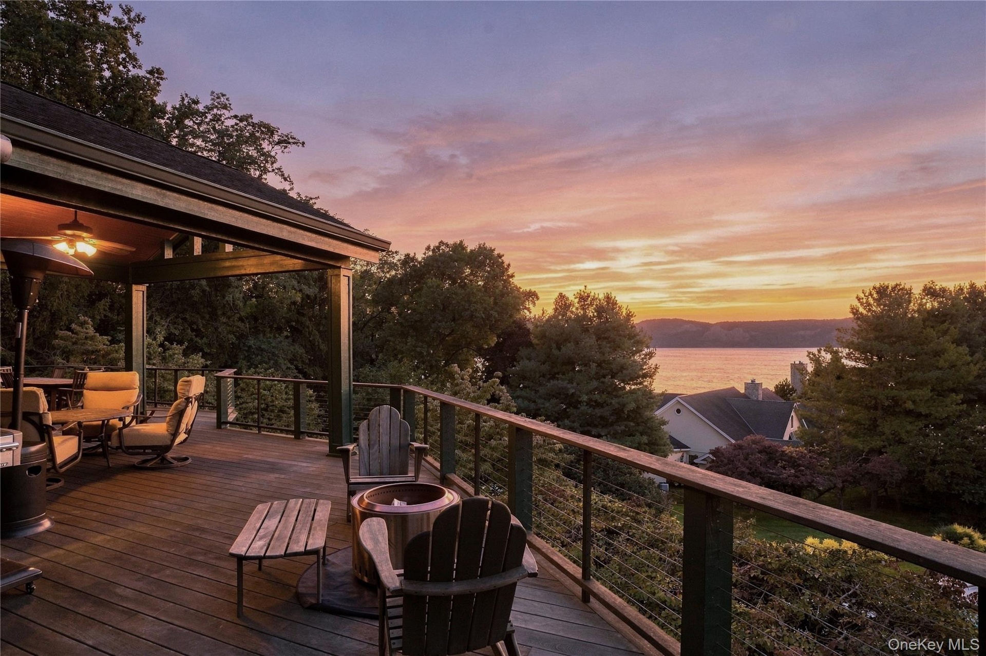 Expansive  1100 Sq foot Ipe deck with a partial covered section, featuring a ceiling fan, cable railing system, and water scenery