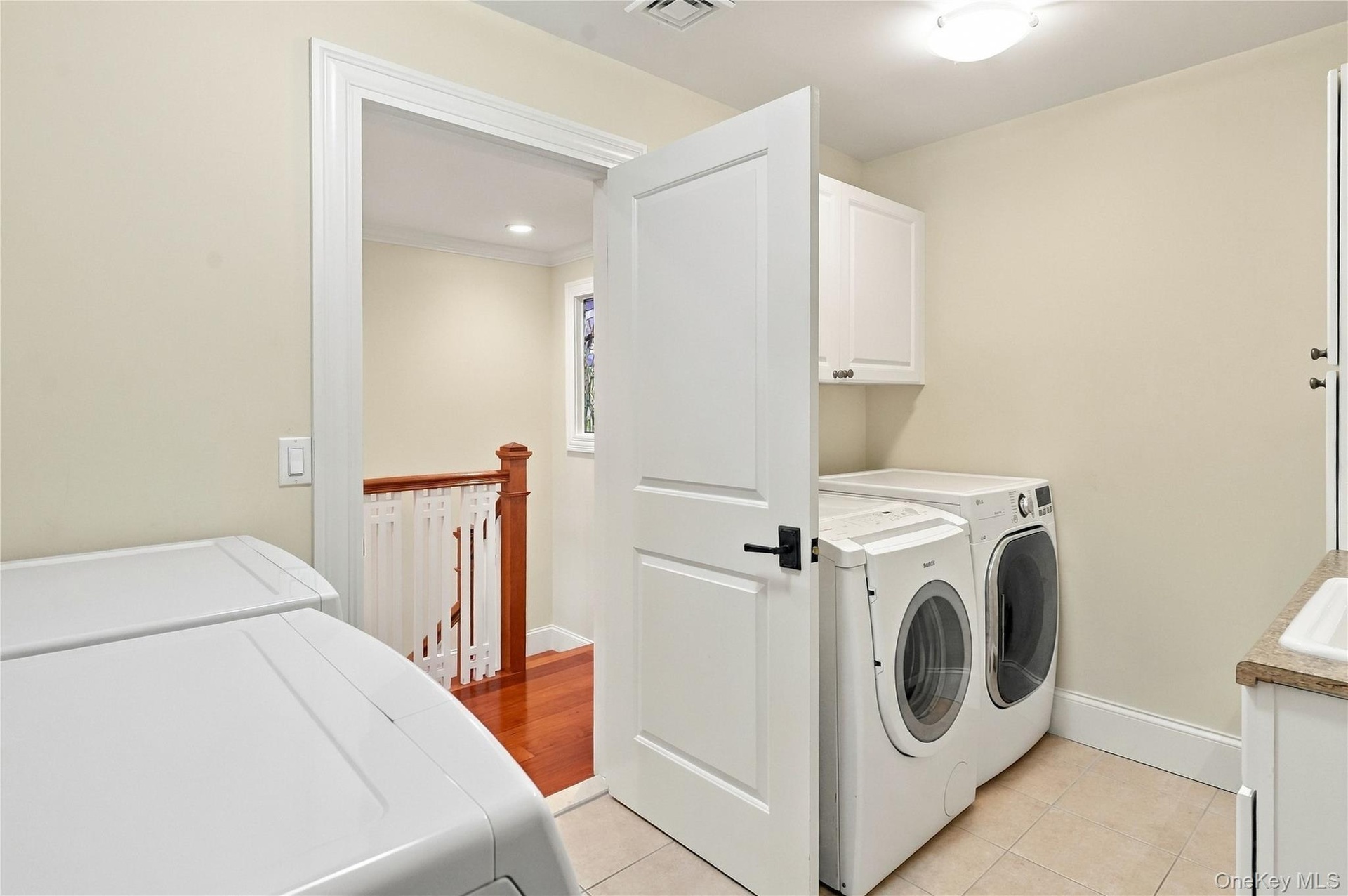 A spacious second-floor laundry room featuring two washers, two dryers, custom cabinetry, and ample storage for added convenience and everyday functio