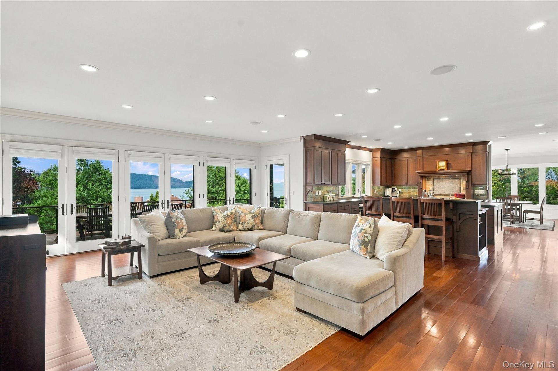 An expansive, open-concept family room and gourmet kitchen featuring custom cherry cabinetry, rich hardwood floors, and walls of glass opening to the 