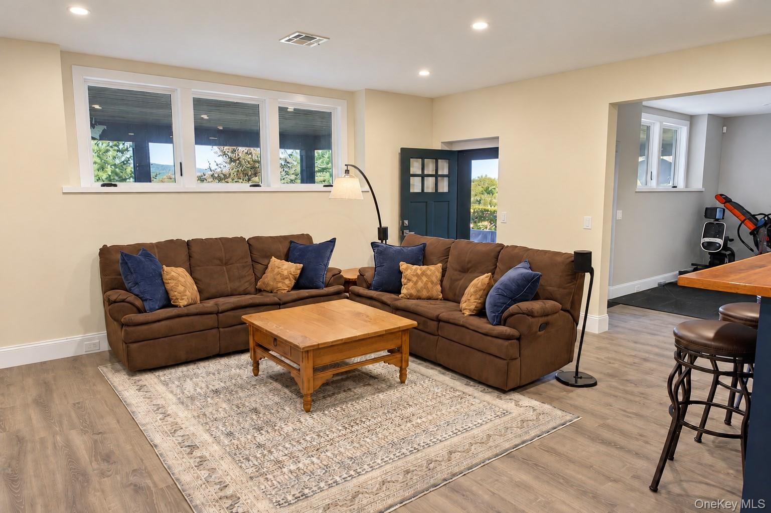 A spacious lower-level living room offering a comfortable setting for relaxation and entertaining, with direct access to the outdoors and adjoining ho