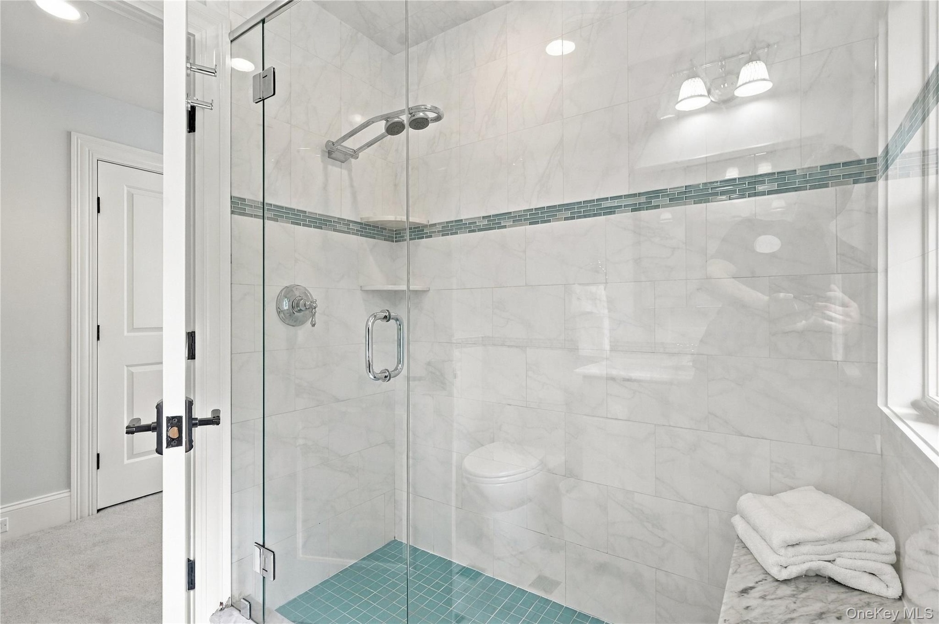 A beautifully designed en-suite bathroom featuring a spacious glass-enclosed shower, elegant finishes, and thoughtful details throughout.