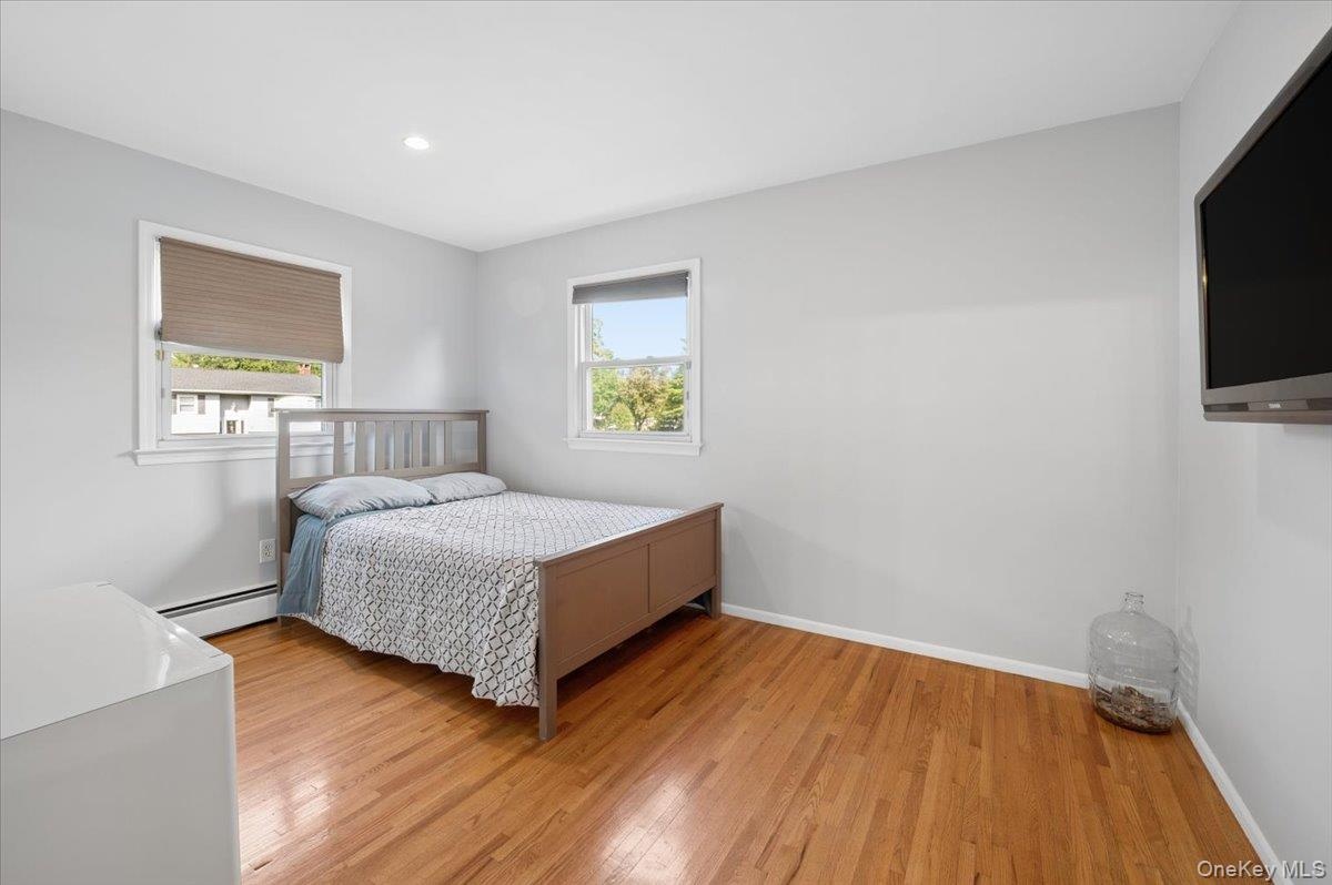 Second bedroom with hardwood floors and recessed lighting.