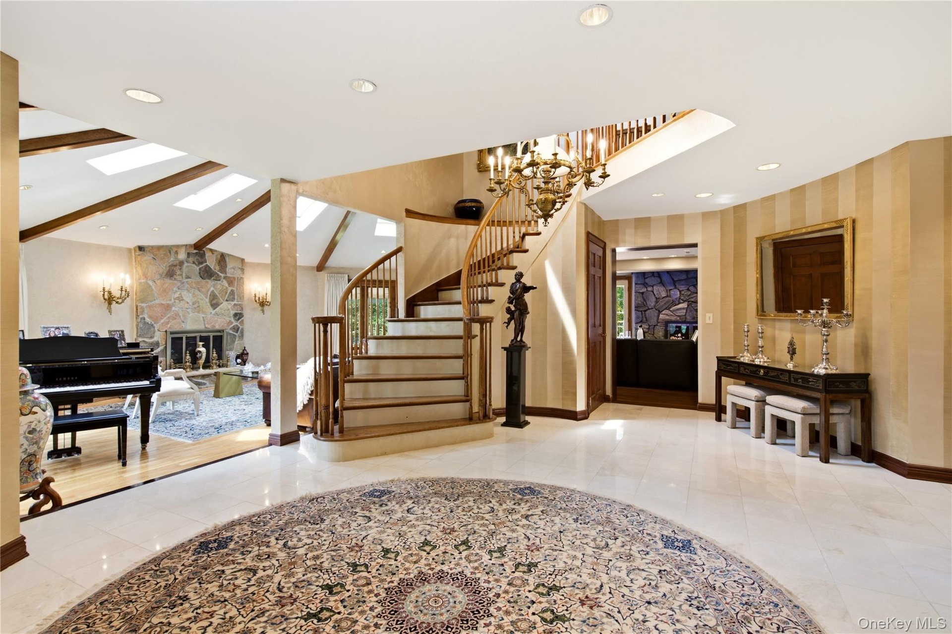 Grand entry with marble flooring, and curved staircase.