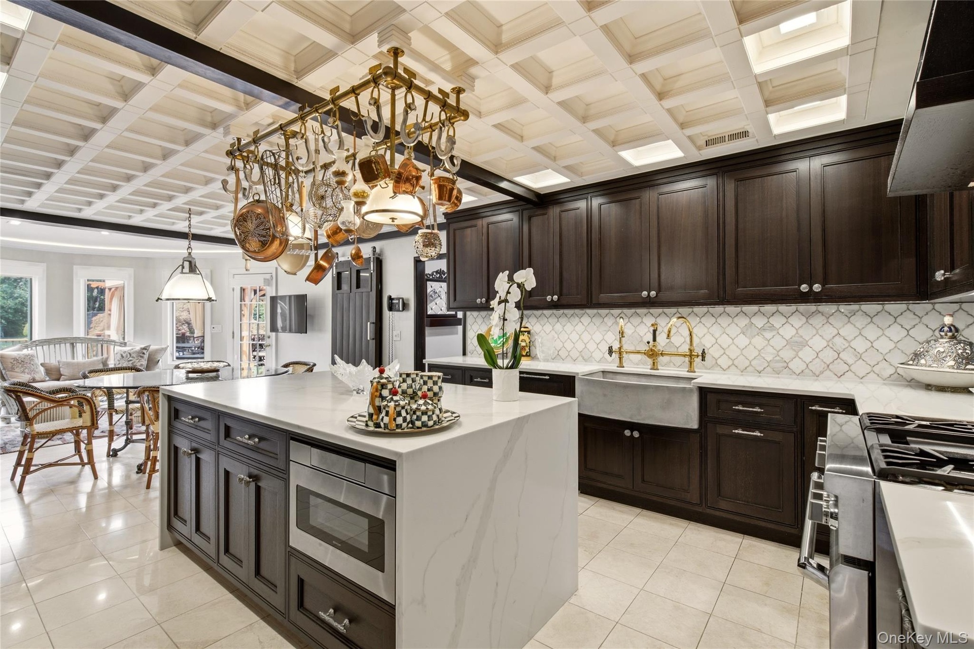 Coffered ceiling with recessed lighting, Farmhouse  stone sink with brass-finish faucet, and a center island with integrated microwave