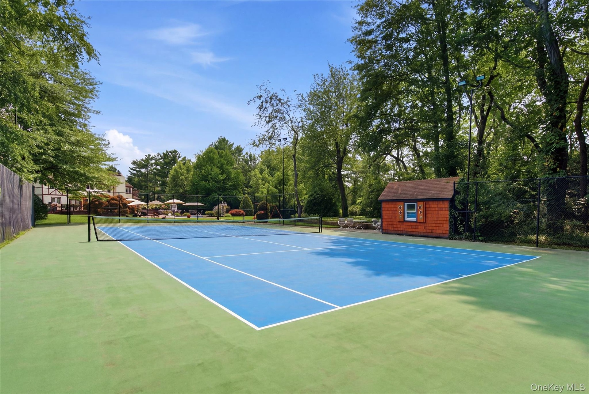 Tennis court featuring a blue playing surface, and perimeter fencing