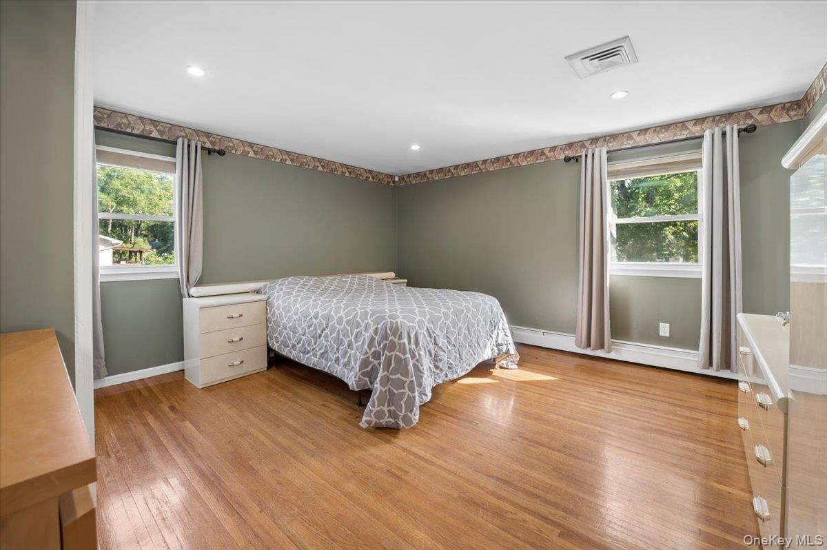 Spacious primary bedroom with ample closets, hardwood floors, recessed lighting and en-suite bath.