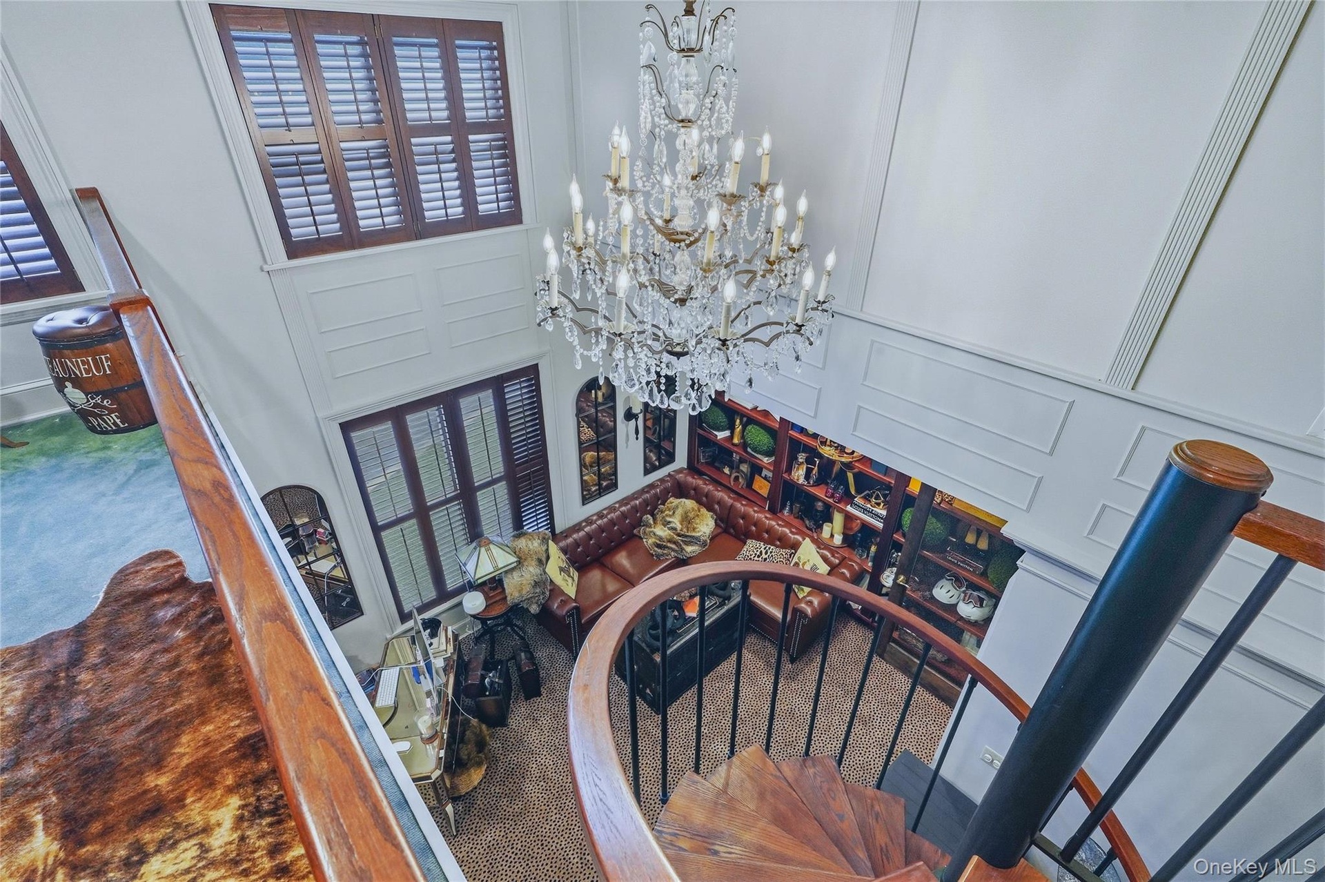Two-story living space with a spiral staircase, a crystal chandelier, and built-in shelving