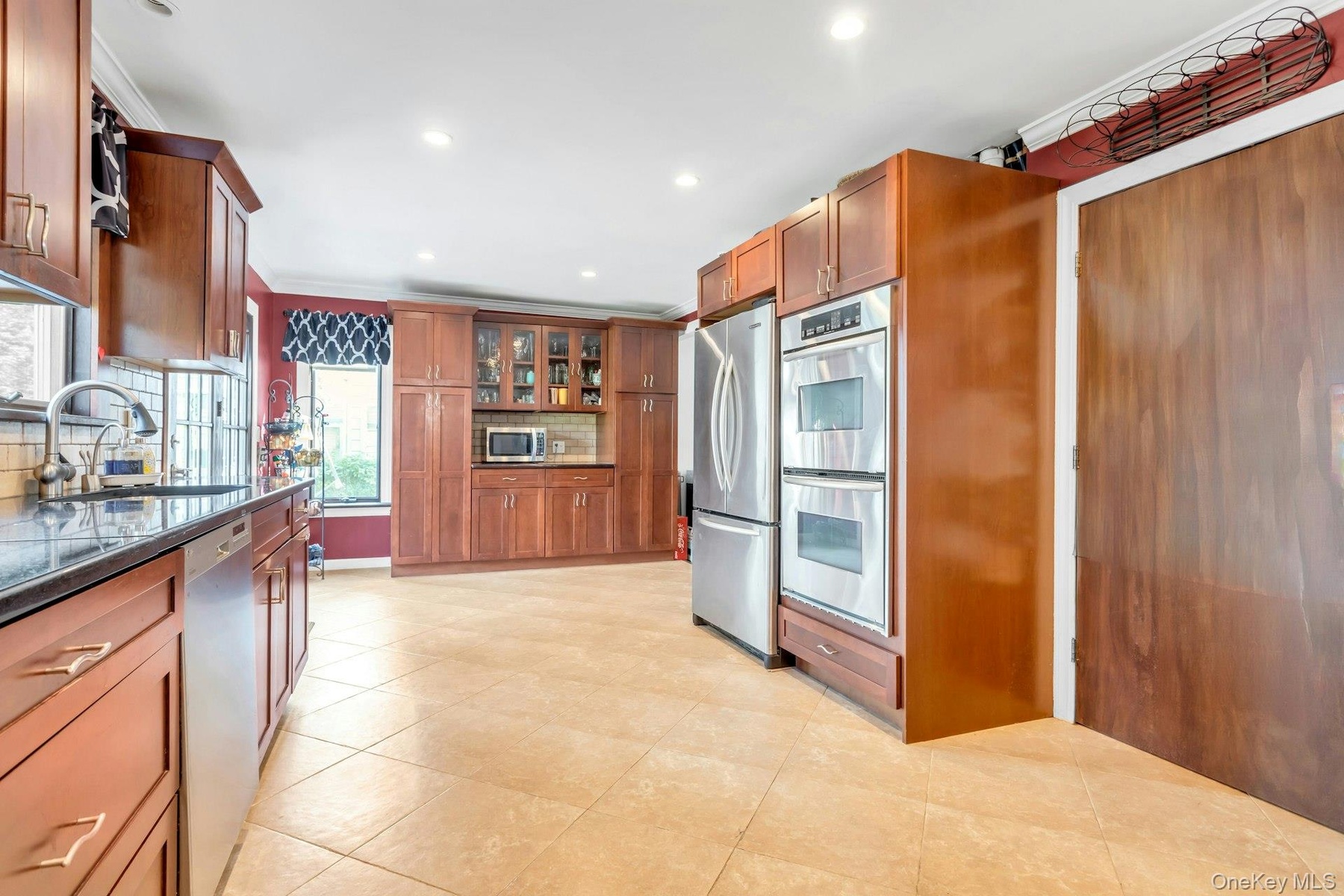 Full kitchen with extensive wood cabinetry, stainless steel appliances, dark countertops, tile flooring, and recessed lighting