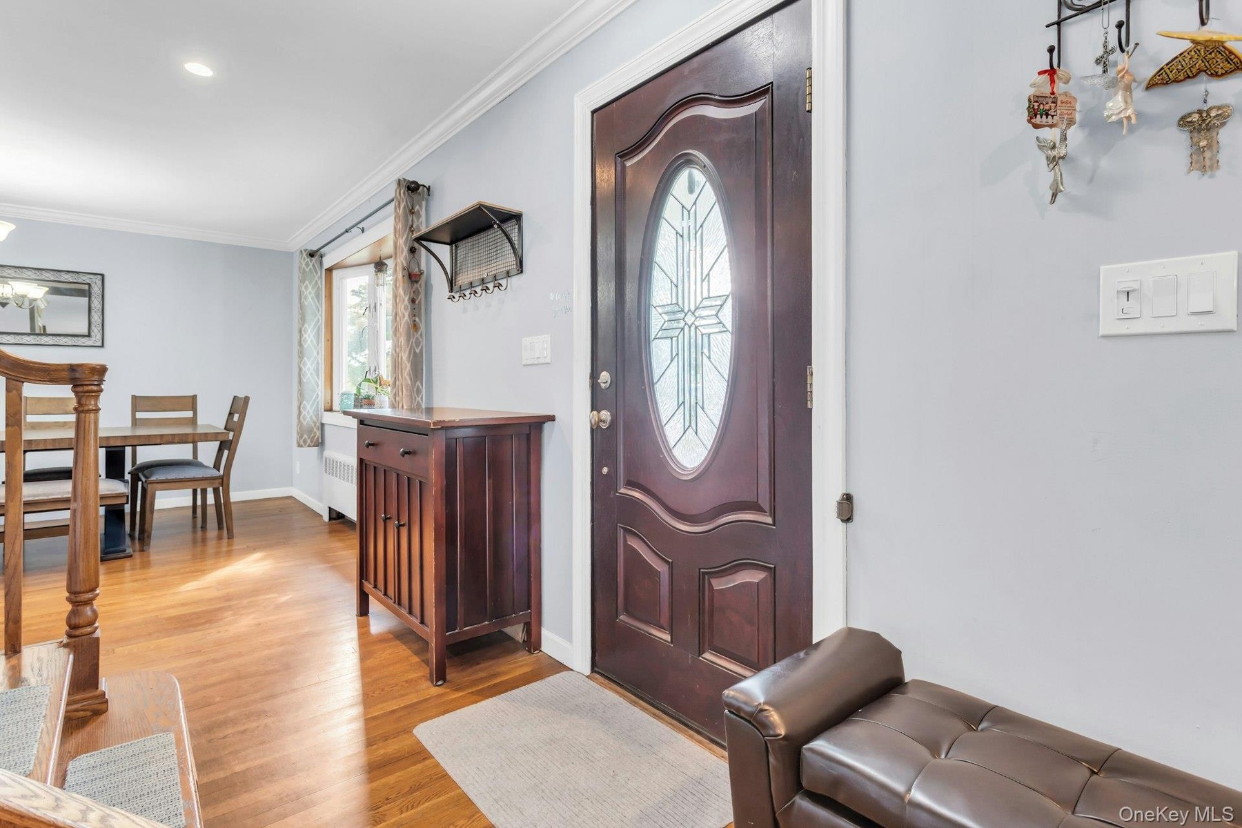 Hardwood flooring, recessed ceiling lighting, crown molding, and a decorative front entry door with an oval glass insert