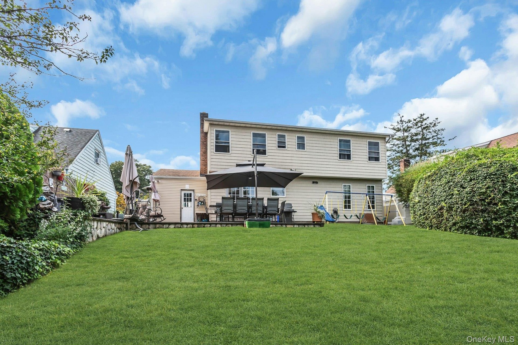 Expansive green lawn with a retaining wall, complemented by mature privacy landscaping