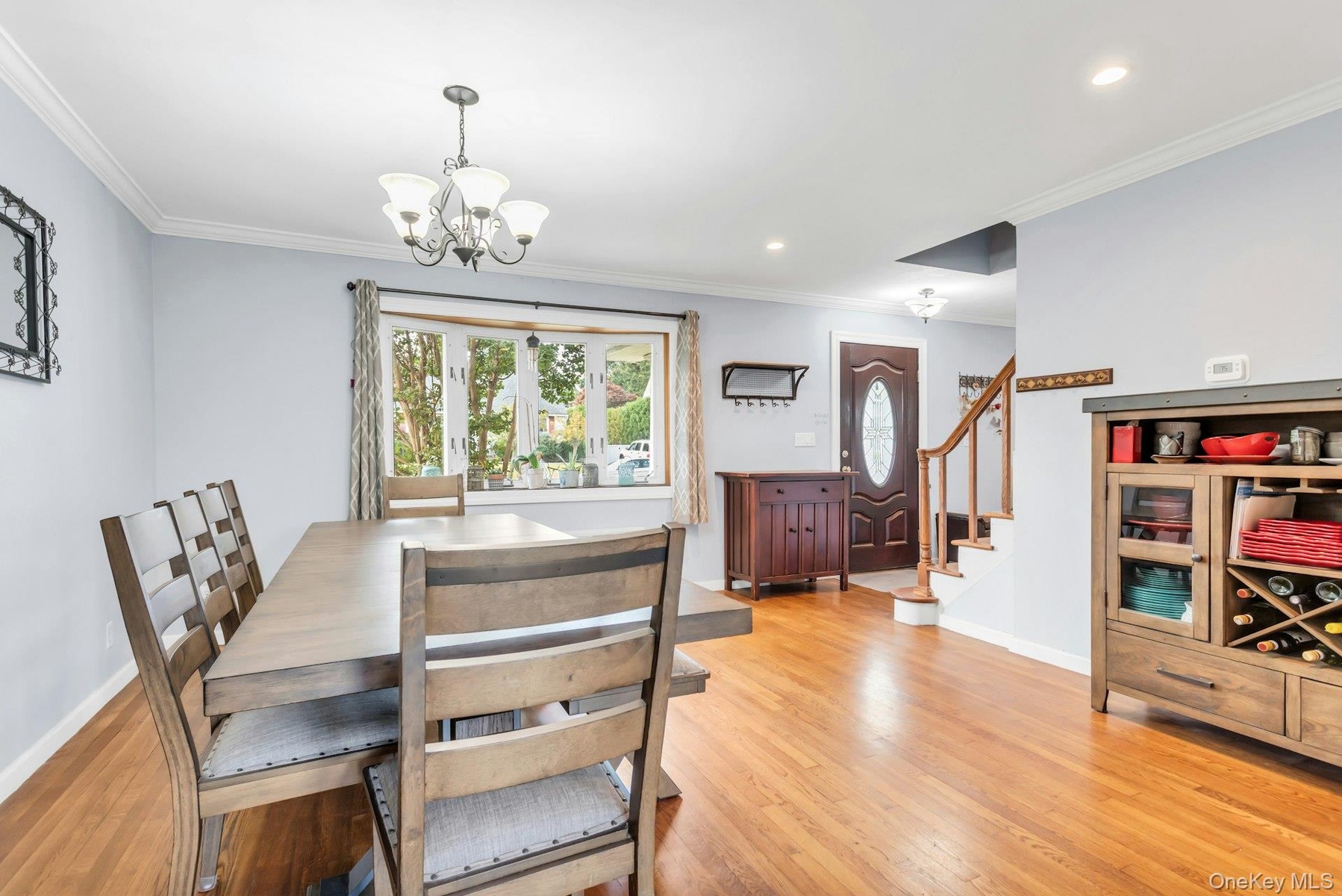 Hardwood flooring throughout, bay window, decorative chandelier, recessed lighting, and a stained wood entry door with oval glass insert