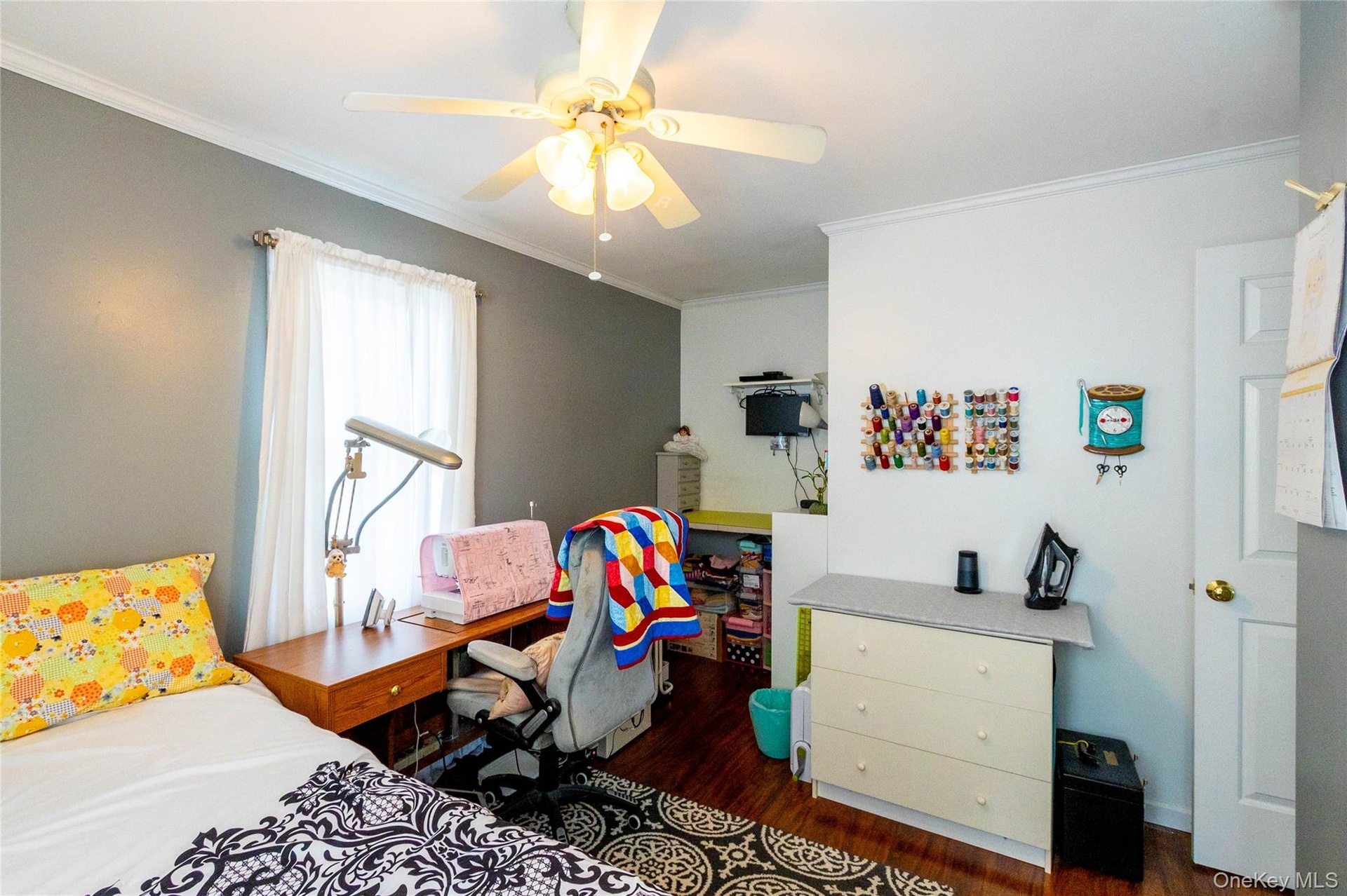 Hardwood-finish flooring, ceiling fan with integrated lighting, crown molding, and a built-in desk area