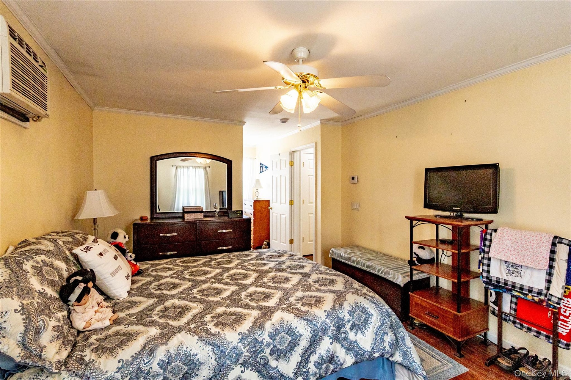 Wall-mounted air conditioning unit, ceiling fan with integrated lighting, and wood-finish flooring
