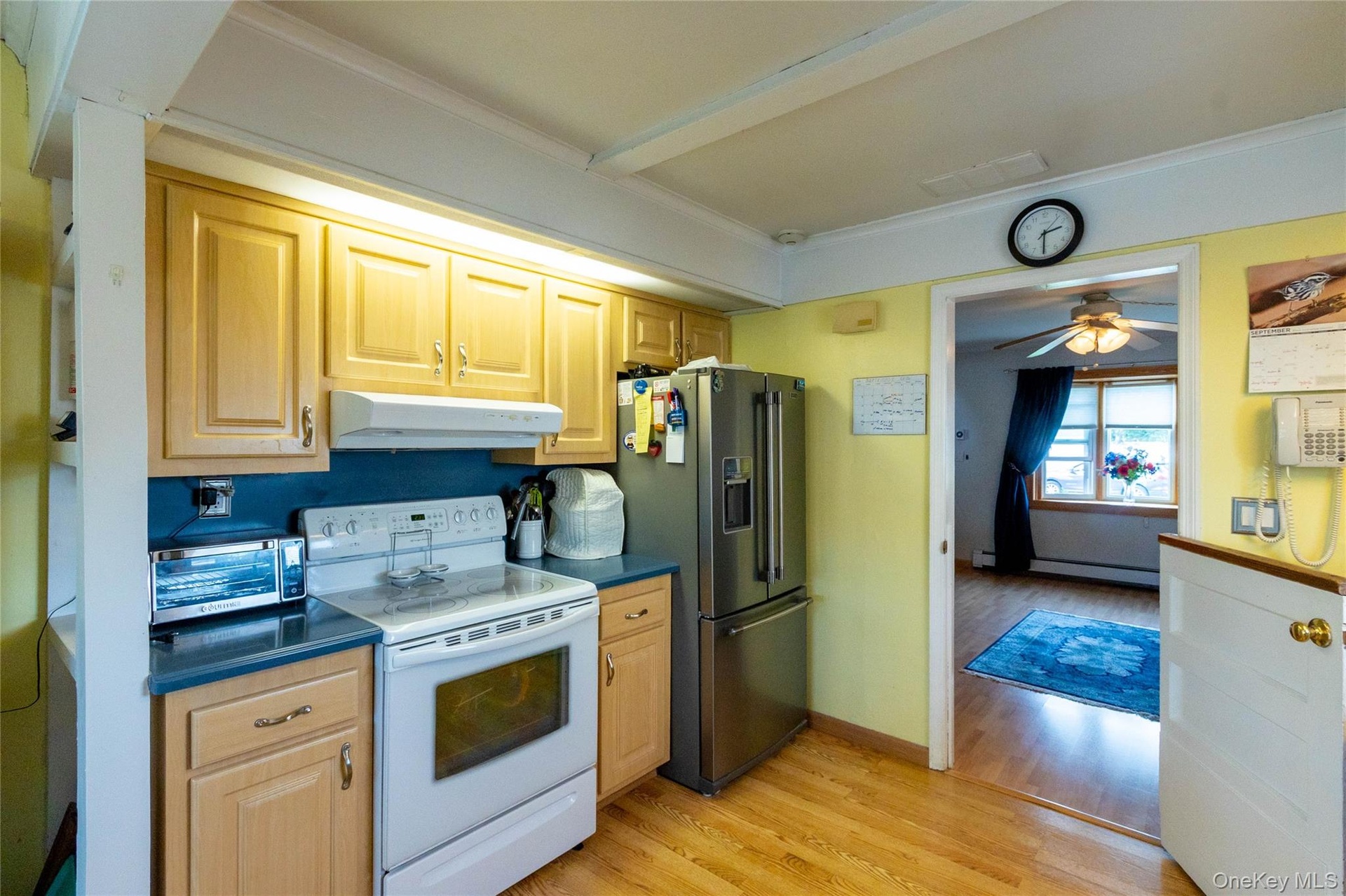 Kitchen with wood-finish flooring, natural wood cabinetry, blue countertops, and stainless steel appliances