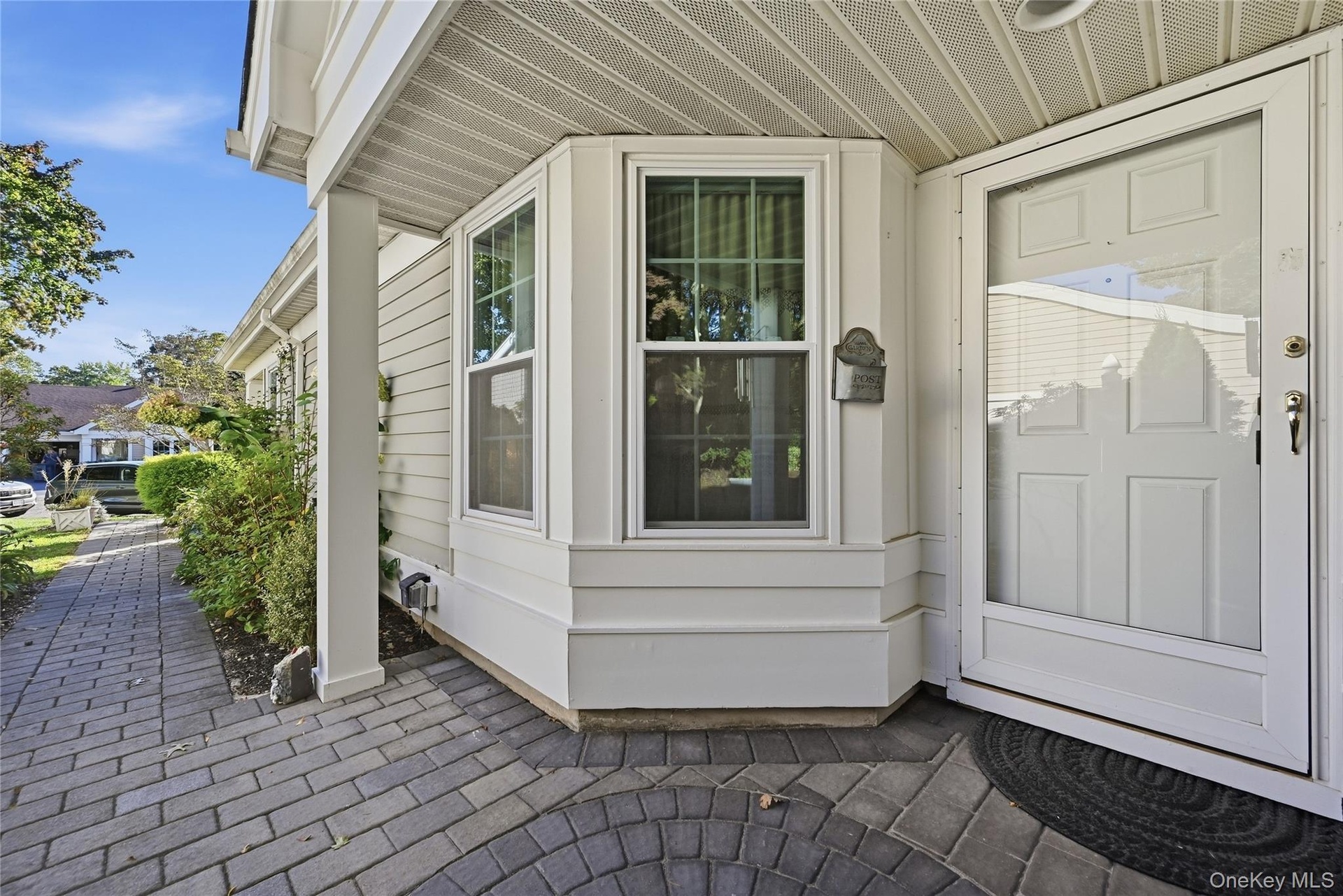 A Brick/Paver Walkway With An Accent Custom Embedded Circle At The Covered Front Entry Leads Into The Home.