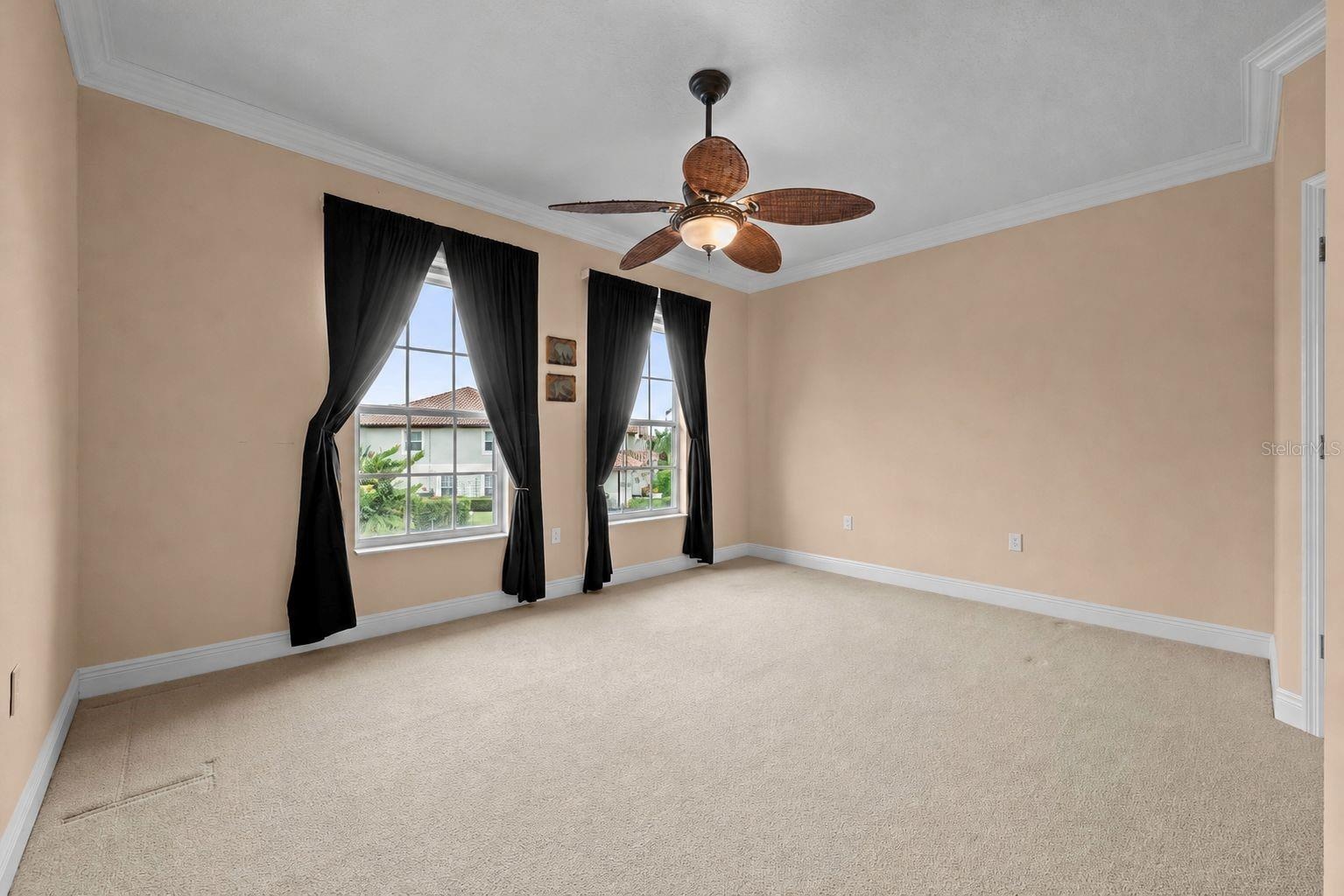 A spacious bedroom with soft natural light, crown molding, and room to make it your own-with walk-in closet