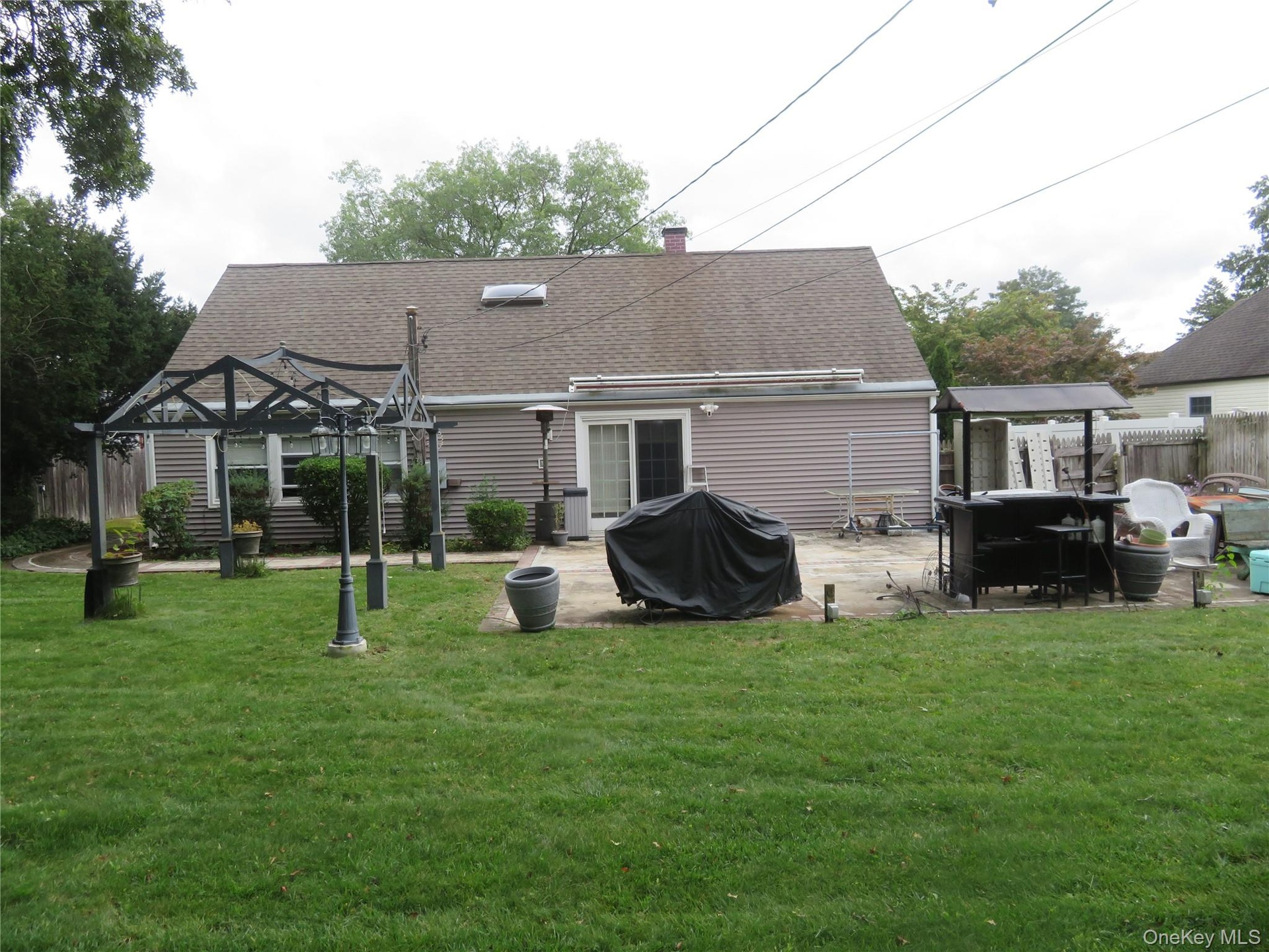 Expansive backyard featuring a manicured lawn, concrete patio, and a built-in pergola structure