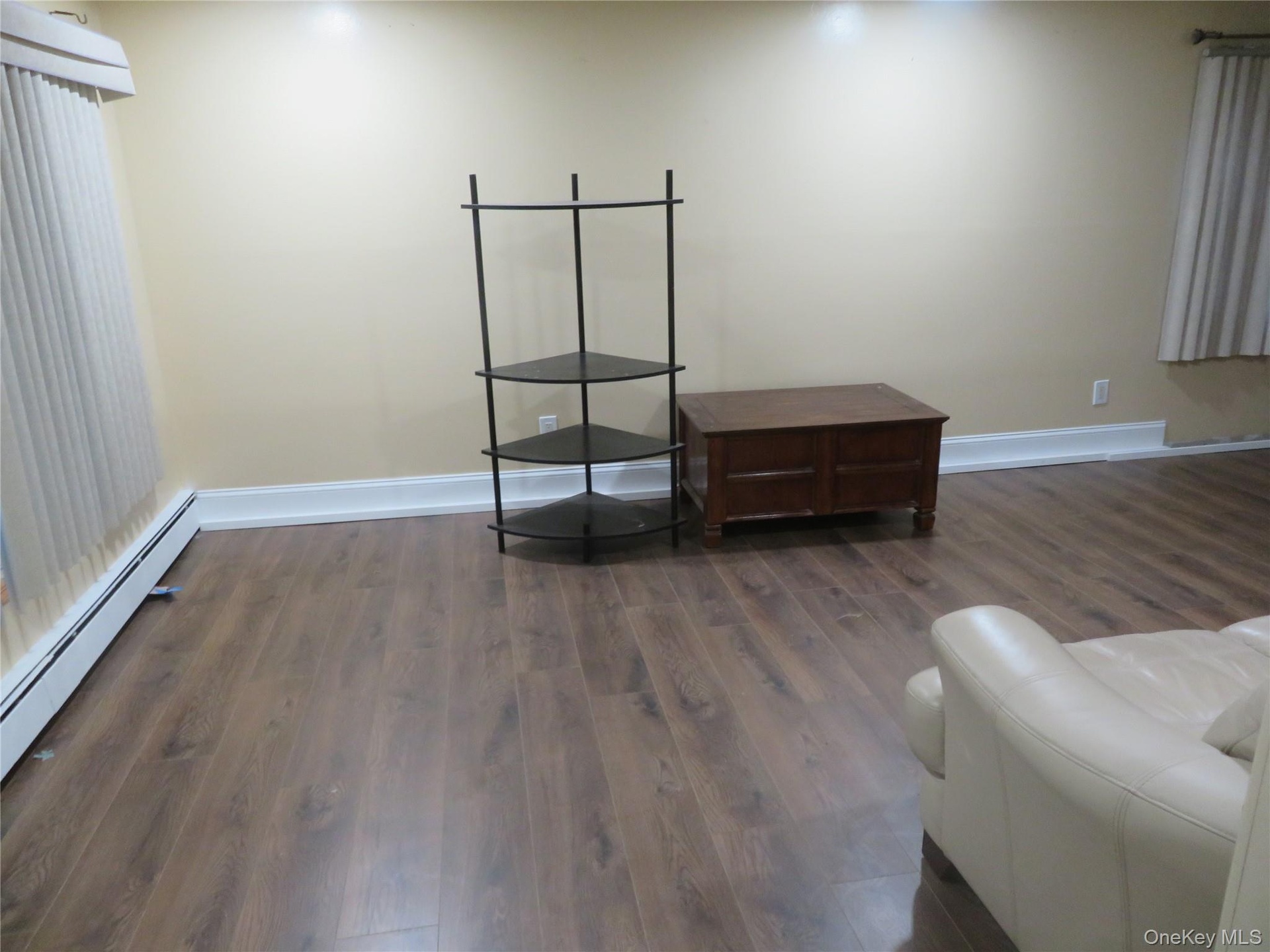Wood-finish flooring with white baseboards, cream-colored walls, and recessed lighting