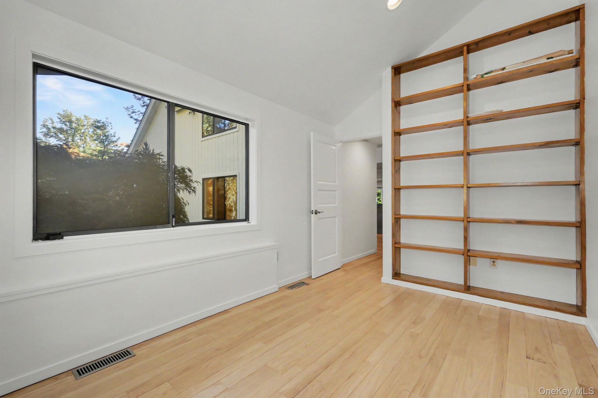 Private office with built-in shelving, large wrap-around windows, and direct access to the primary suite.