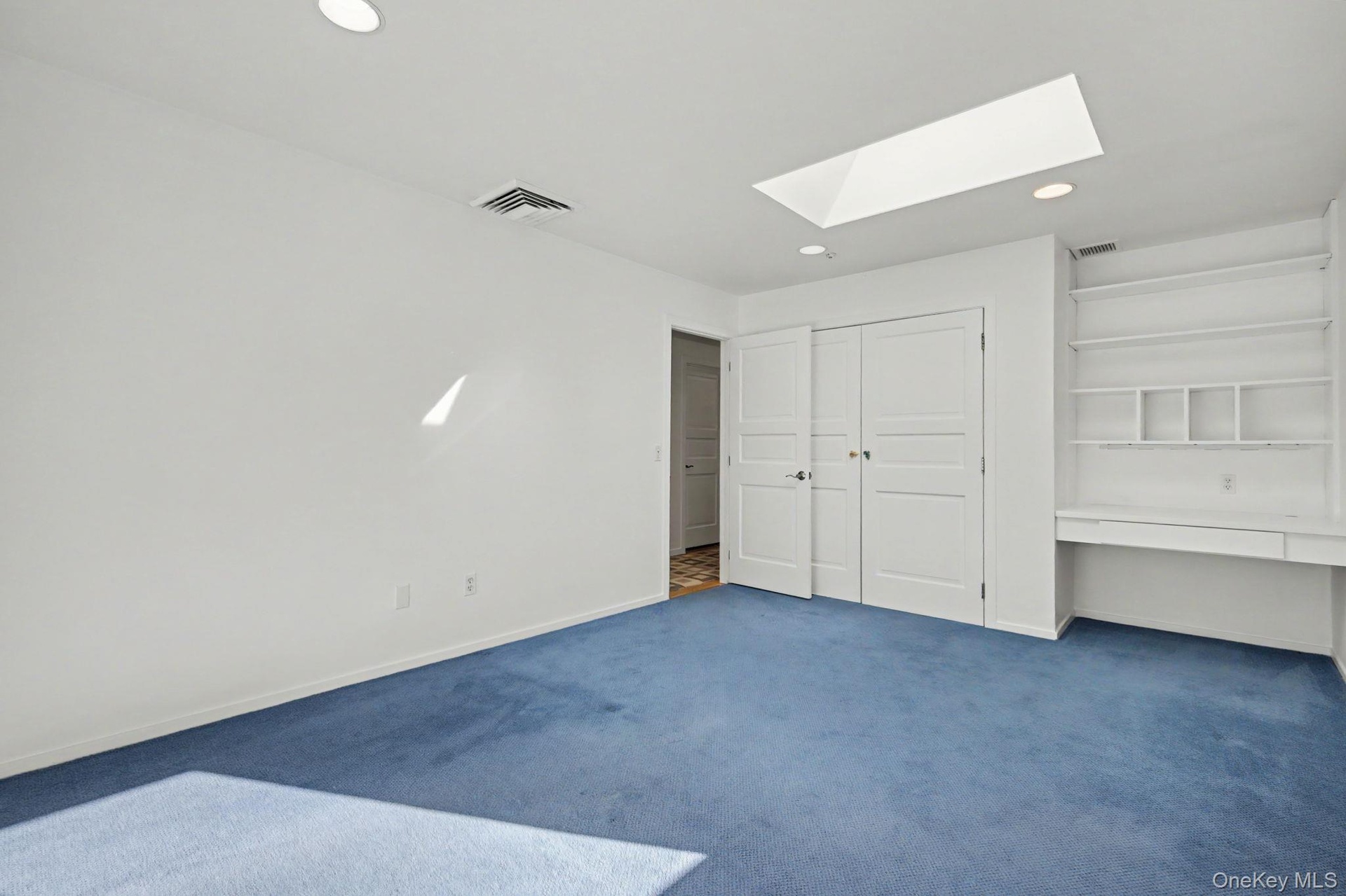 Bedroom 3 with skylight and built-in desk with shelving.