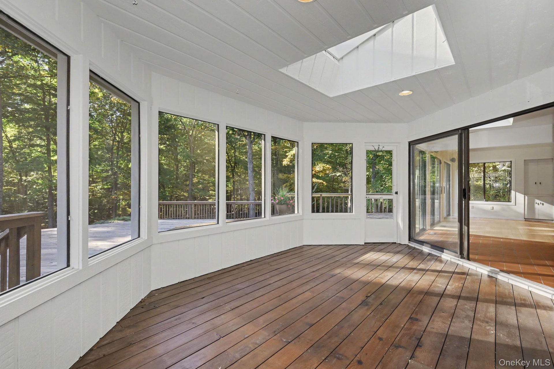 Screened porch with skylight and peaceful woodland views, accessible from the kitchen-dining area and deck.