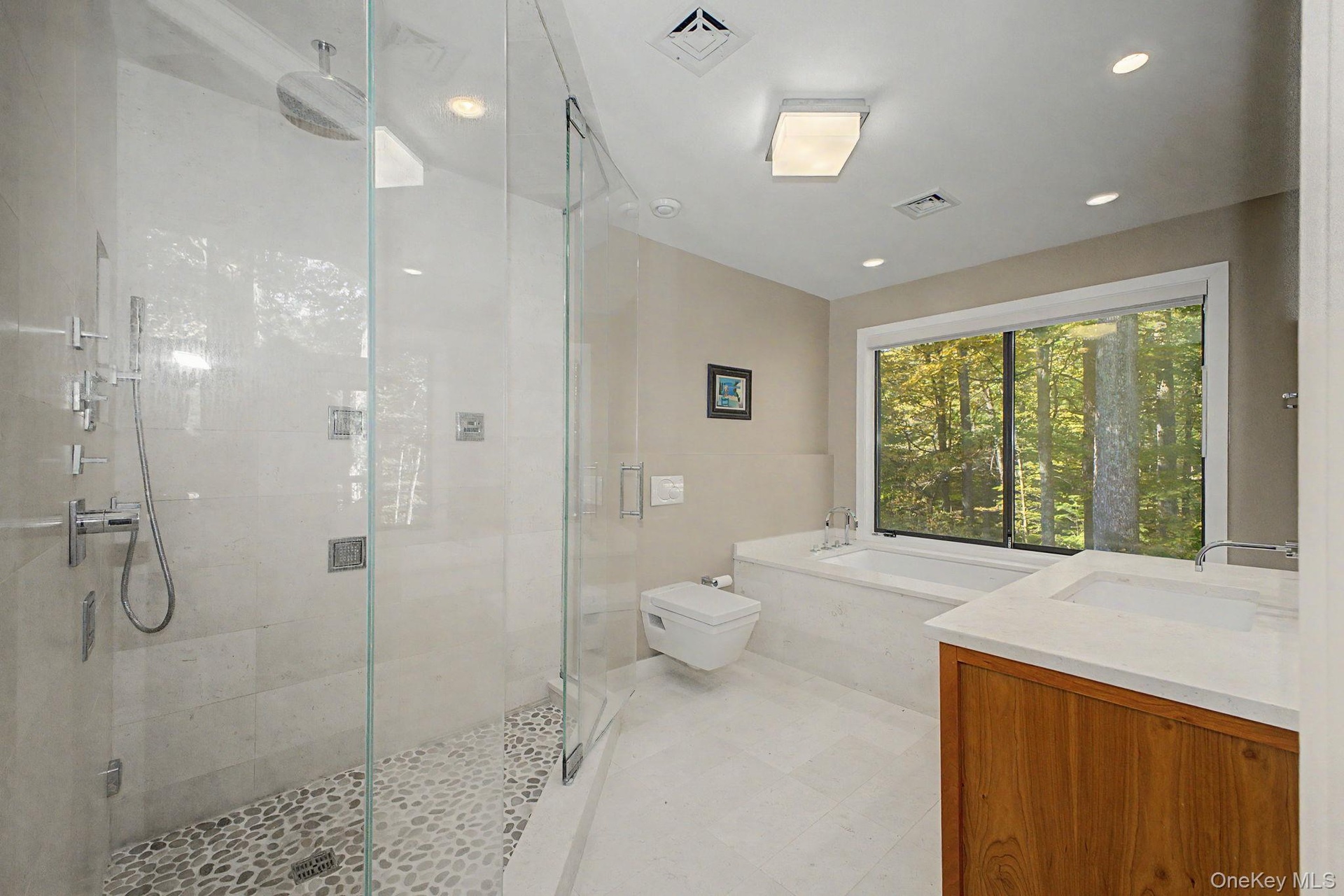 Light-filled primary bath with glass-enclosed steam shower, Bain Ultra tub, and serene woodland views.