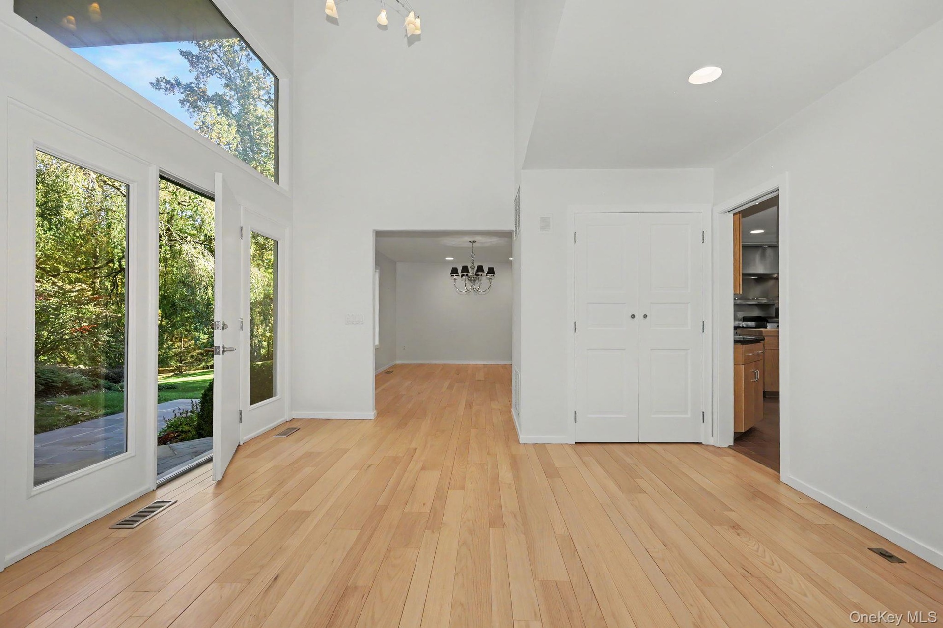 Spacious, light-filled entry foyer with high ceilings, expansive windows, and newly refinished hardwood floors.