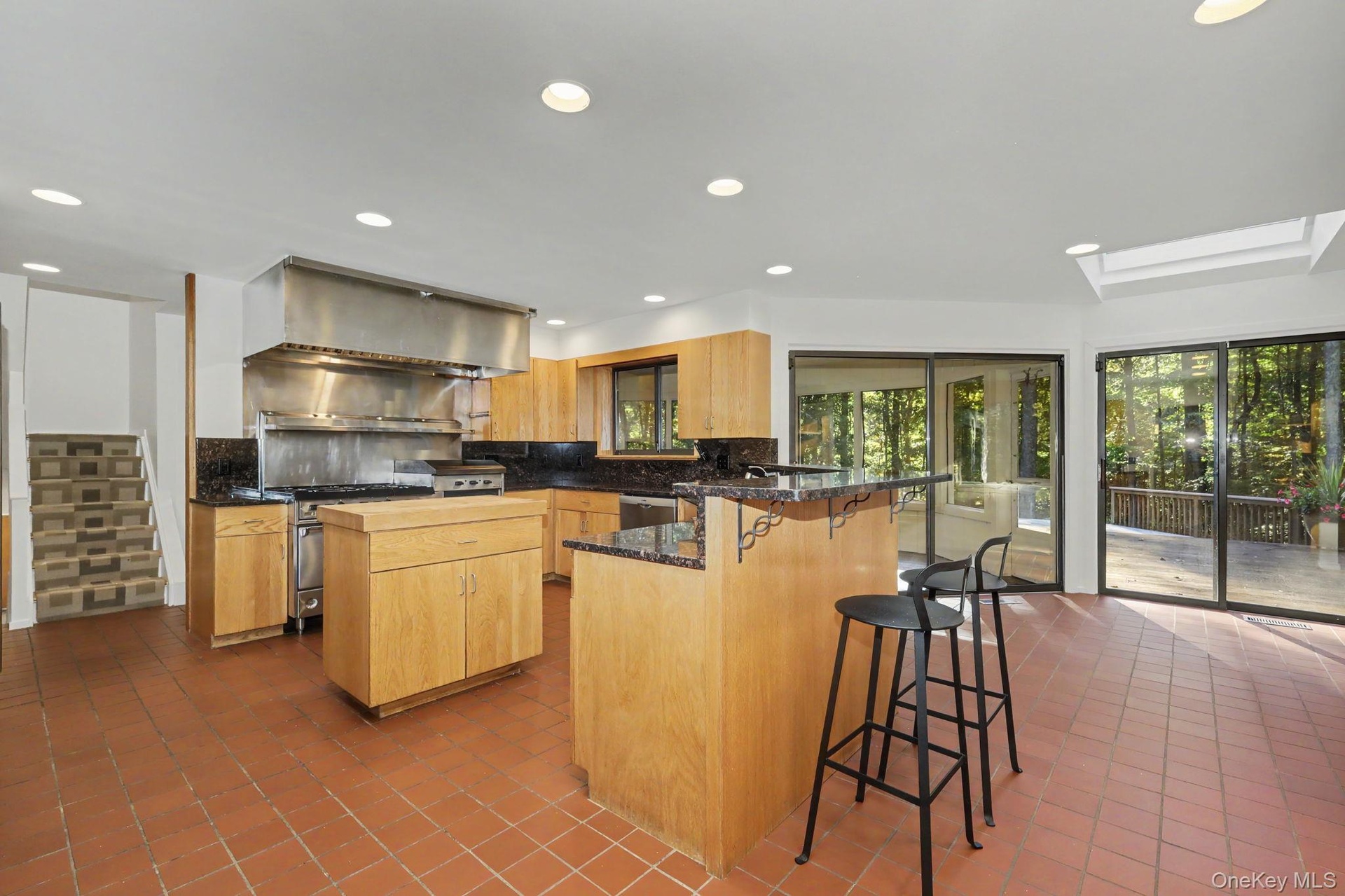 Light-filled kitchen with a center prep island and adjoining dining area with sliding glass doors to the screened-in porch and deck.