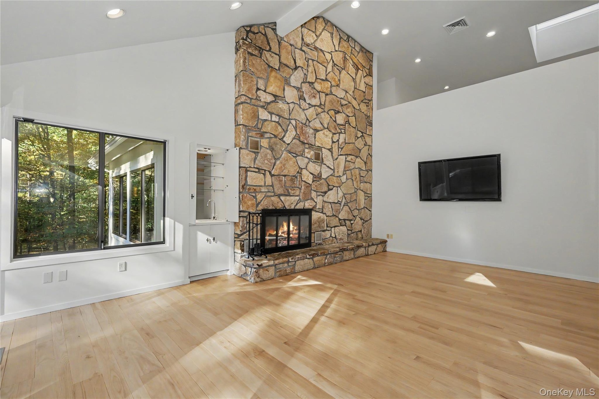 Inviting family room with cathedral ceilings, skylights, and a striking stone fireplace extending to the ceiling.