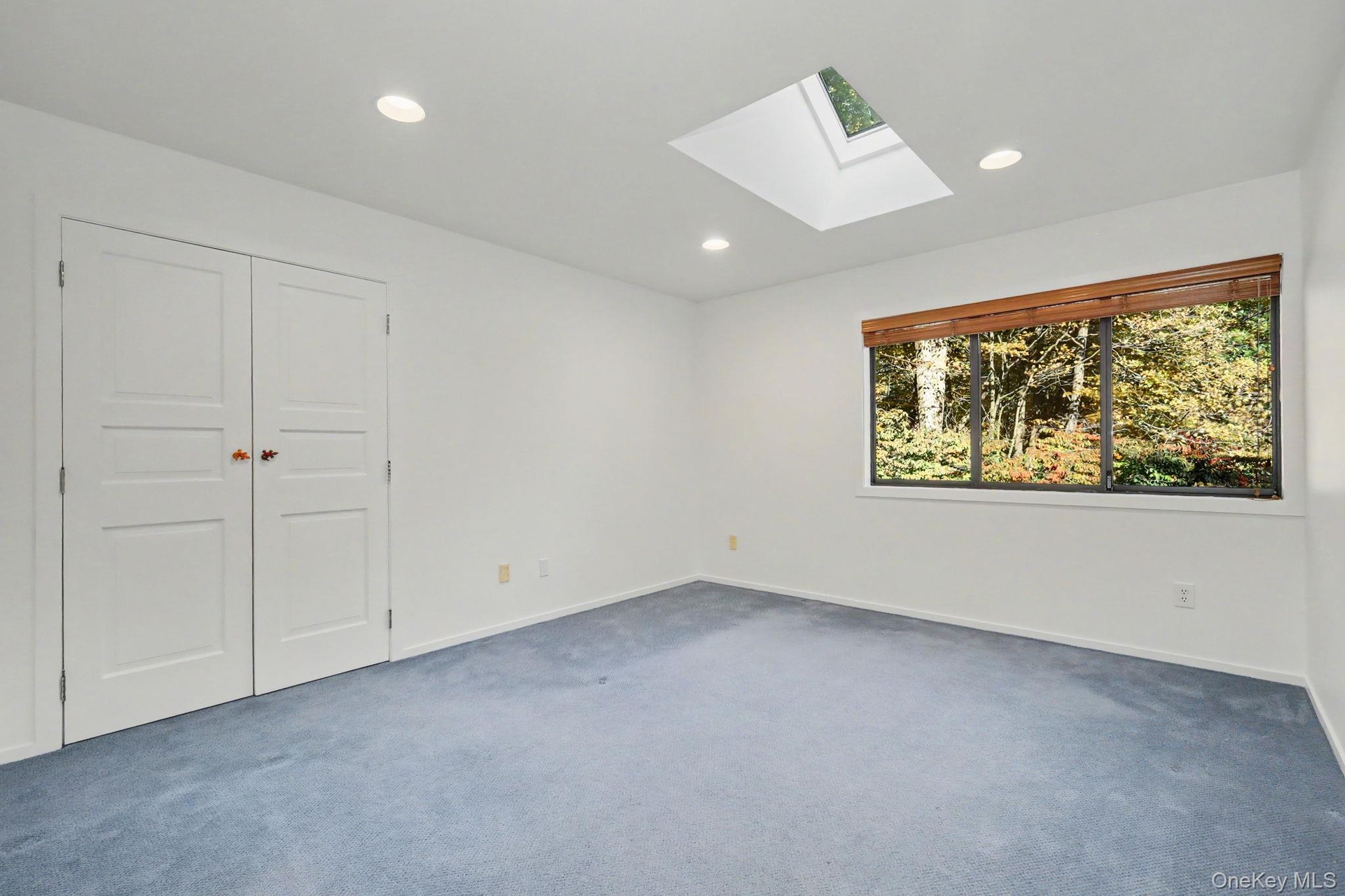 Bedroom 2 with skylight and large window overlooking the backyard.