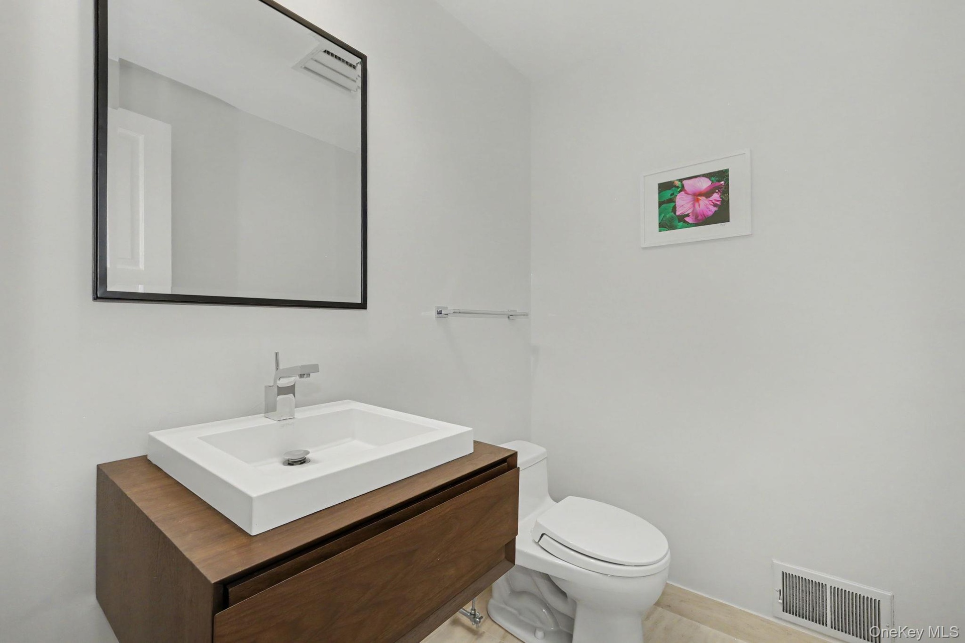Powder room conveniently located near the office, featuring a floating wood vanity and a vessel sink.