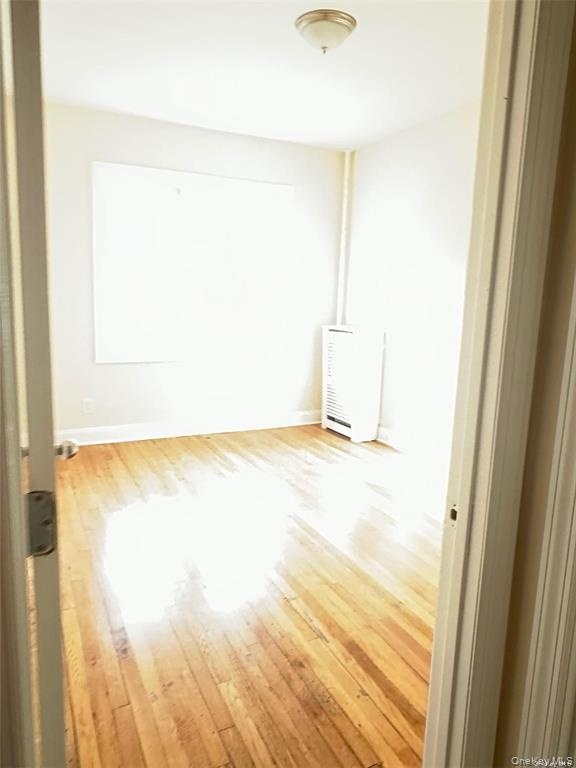 Hardwood flooring, flush-mount ceiling light fixture, baseboard heating unit, white wall finish