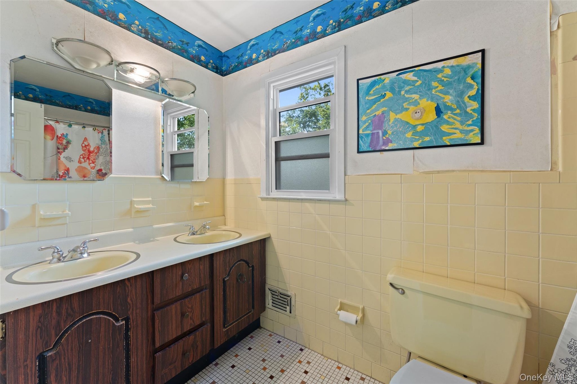 Vanity with two sinks, wood-finish cabinetry, and overhead lighting.
