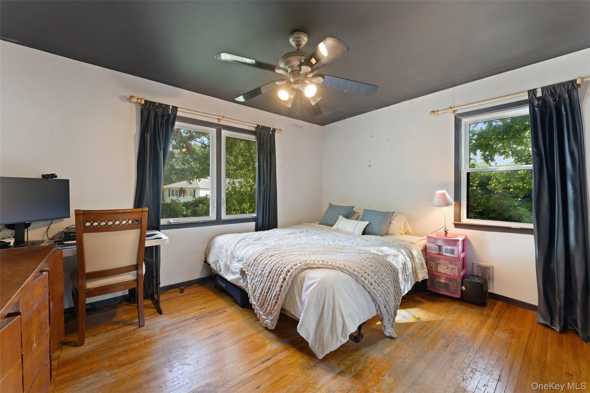 Hardwood flooring, painted light grey walls, dark-painted ceiling, and a ceiling fan.