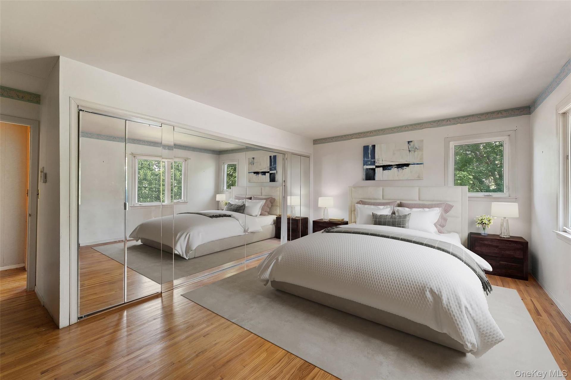 Primary Bedroom is virtually staged. Hardwood flooring, mirrored sliding closet doors, with multiple windows.