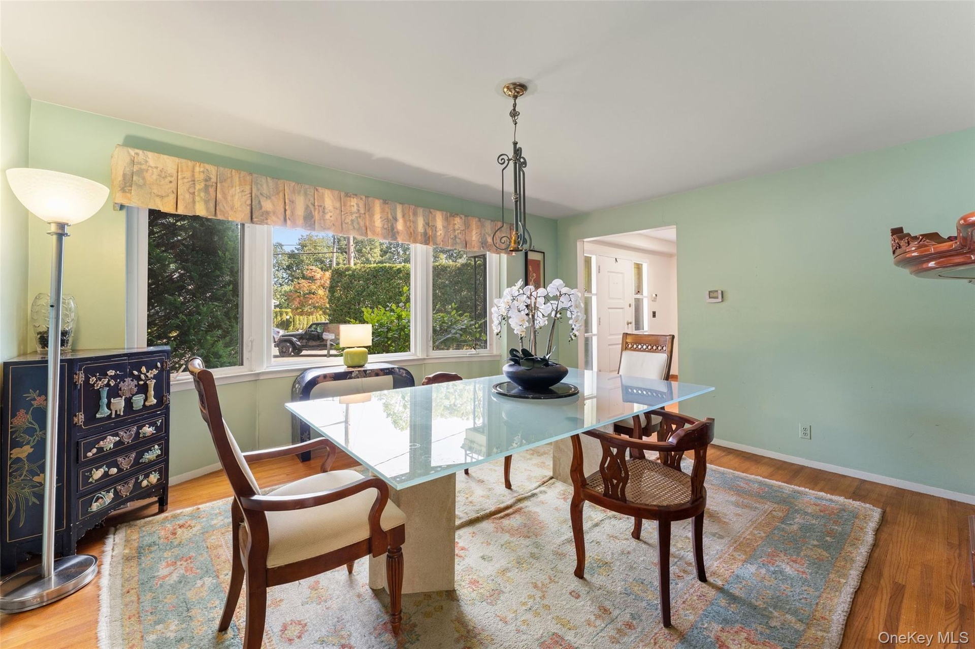 Hardwood flooring, broad window with valance, and a ceiling light fixture.