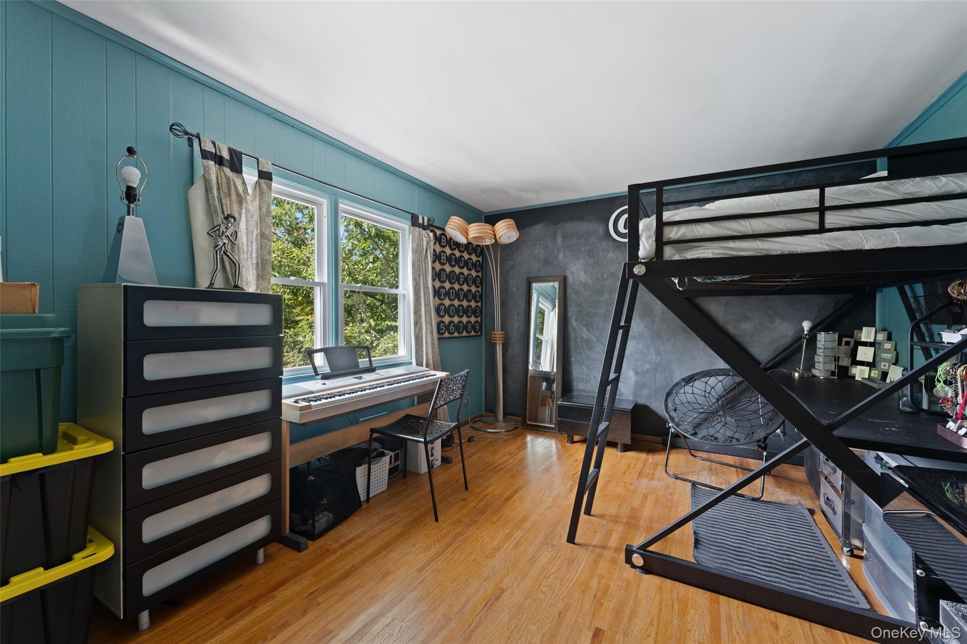 Hardwood flooring with a white ceiling and teal panel walls.